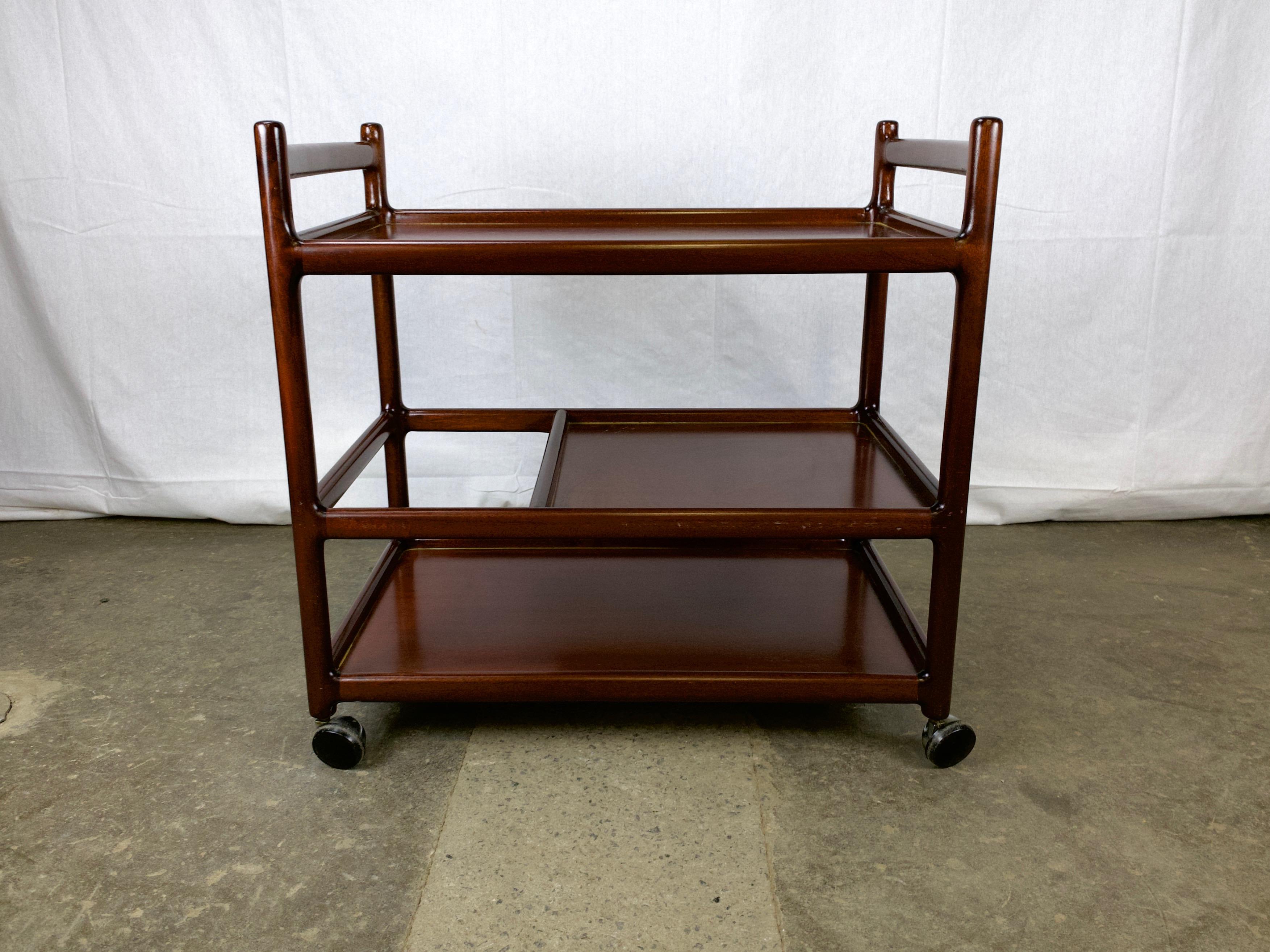Tea trolley or bar cart designed by Johannes Andersen and made in Denmark by CFC Silkeborg. The frame is solid mahogany in a deep rosewood stain.

The cart features the graceful curves that are typical of Andersen's work, as the horizontal rungs