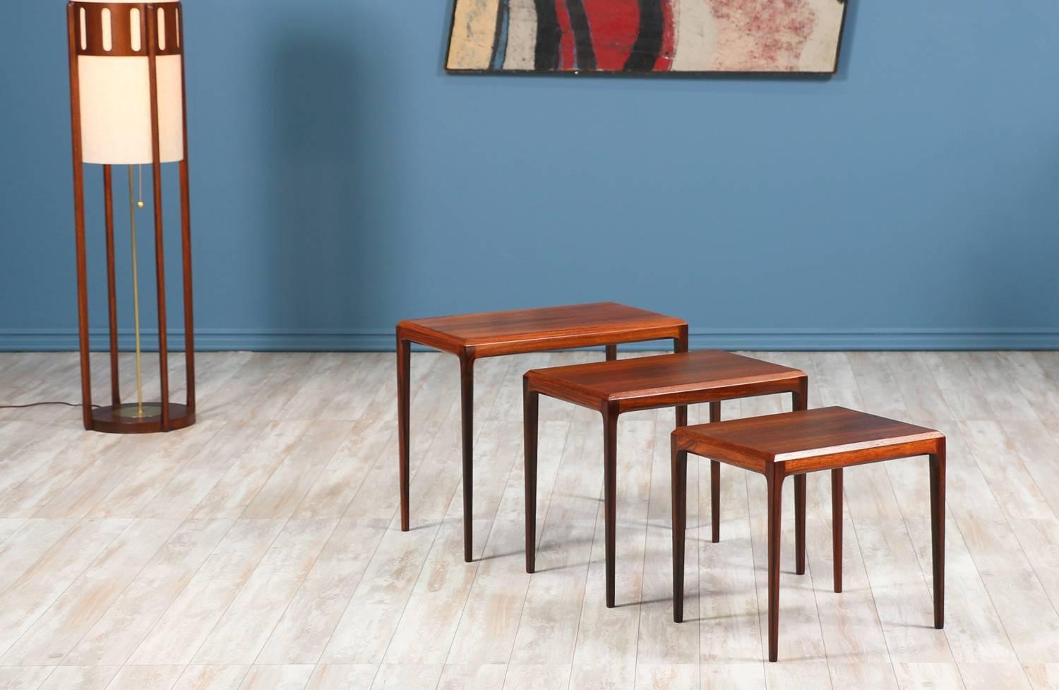 Nesting tables designed by Johannes Andersen for CFC Silkeborg and manufactured in Denmark circa 1960’s. This set of three tables is made of exotic wood with beveled edges and tapered legs, featuring a beautiful grain throughout. The design allows