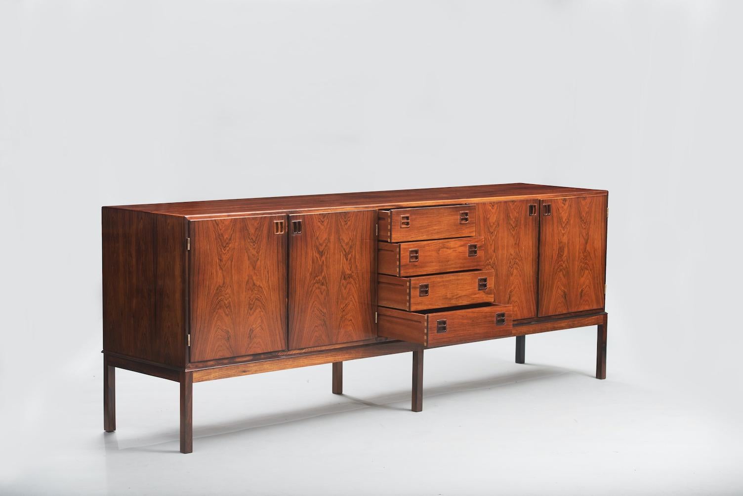 Johannes Andersen long sideboard in veneered rosewood, front with four doors enclosing shelves and four drawers, frame with legs in solid rosewood. Produced by Bernhard Pedersen & Son.