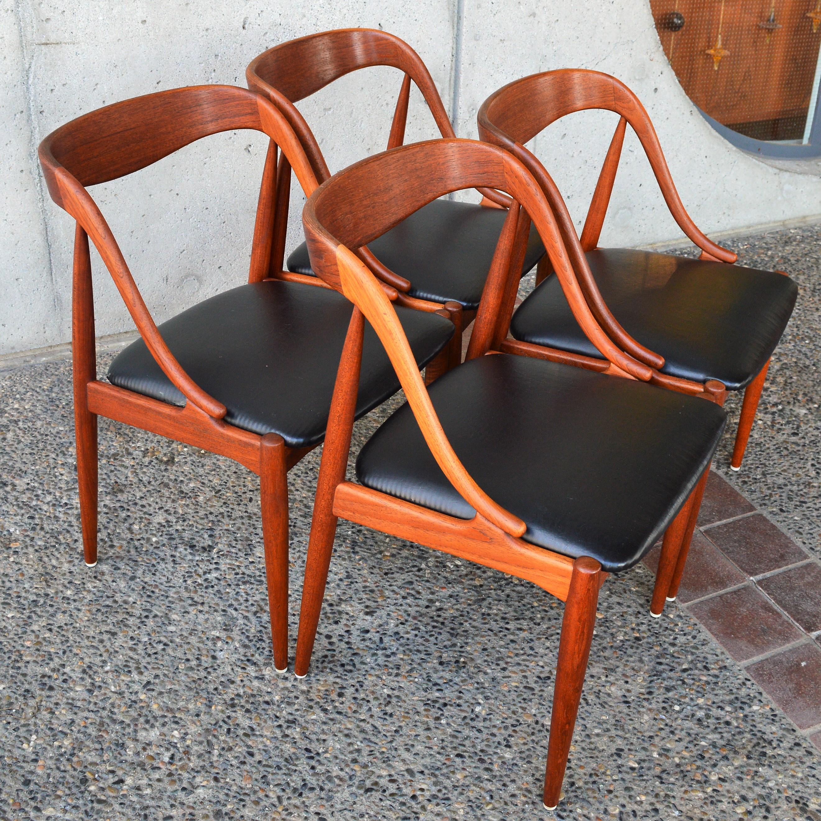 This stellar set of 6 Danish Modern teak dining chairs are two models designed by Johannes Andersen for Uldum Mobelfabric - 4 sculptural side chairs and 2 armchairs to serve as head or captains' chairs, all in matching black vinyl. The side chairs