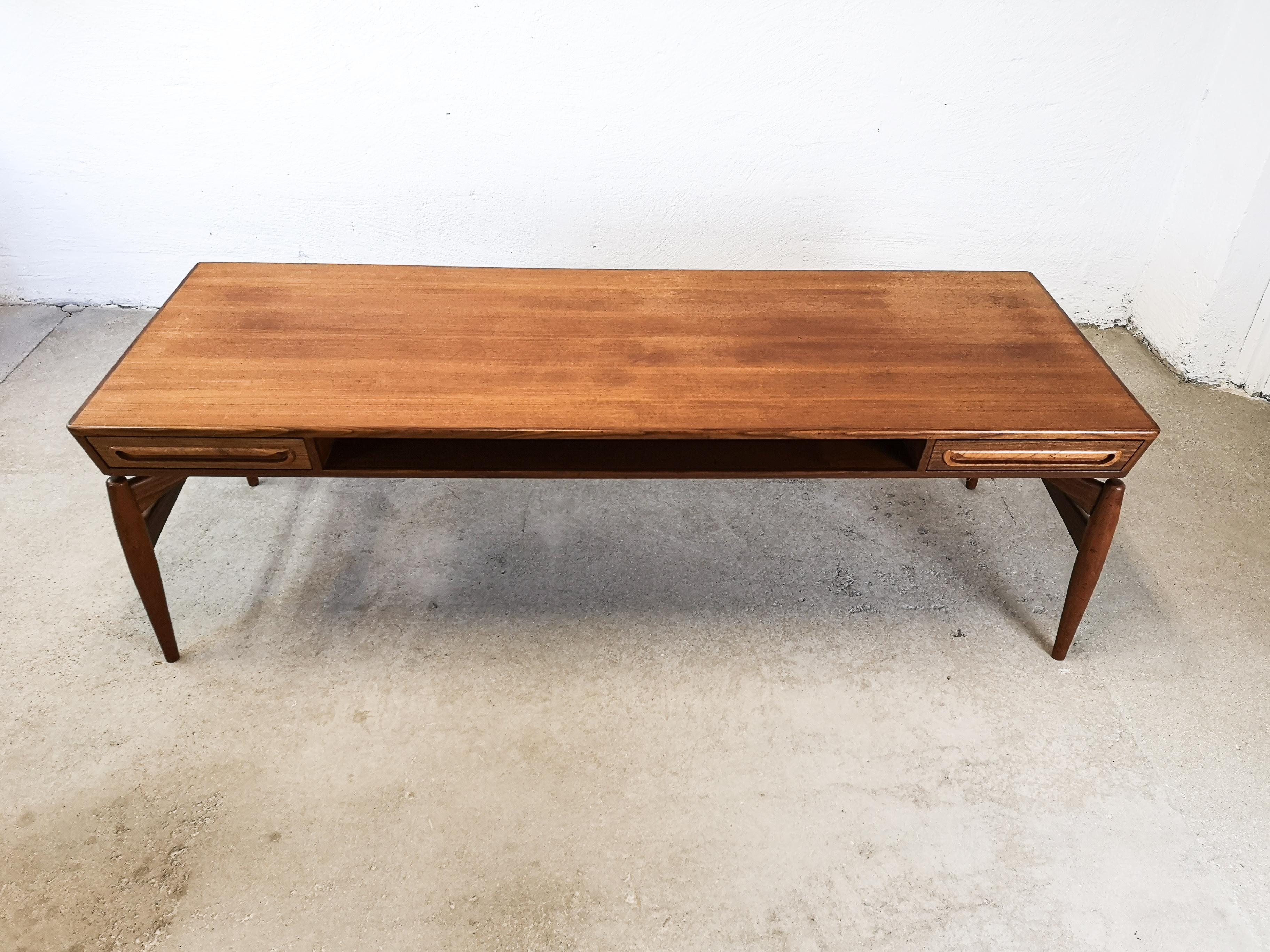 Johannes Andersen teak coffee table for Trensum; tabletop built on a sculpted stand, the coffee table is made with teak, mahogany and walnut woods and produced by Trensum during the 1960s.

 Two drawers with carved pulls that can be opened from