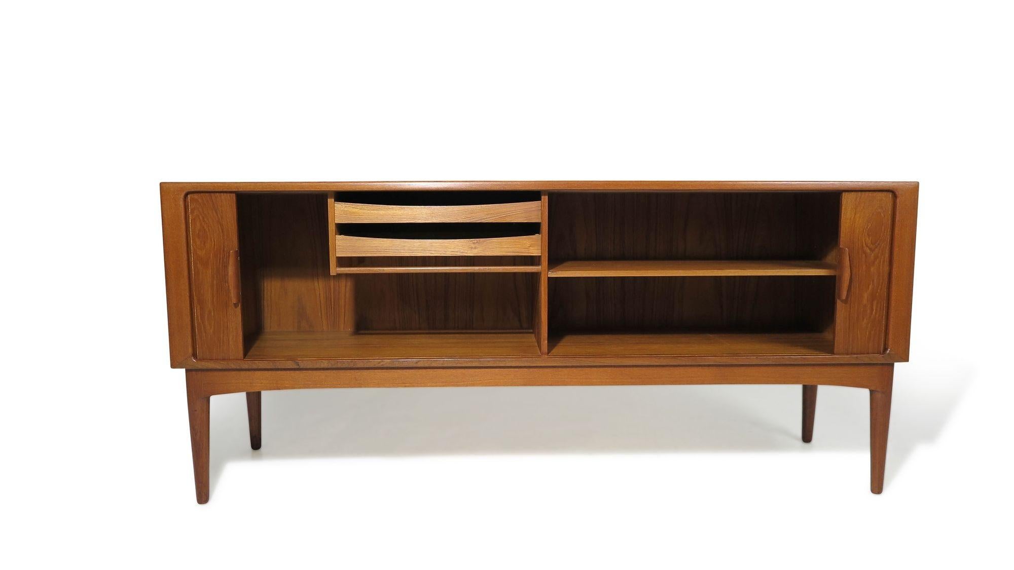 Danish teak credenza designed by Johannes Andersen for Uldum Møbelfabrik, 1955, Denmark. This finely crafted cabinet, made of teak with mitered corners, features tambour doors with sculpted pulls. These doors open to reveal an interior with