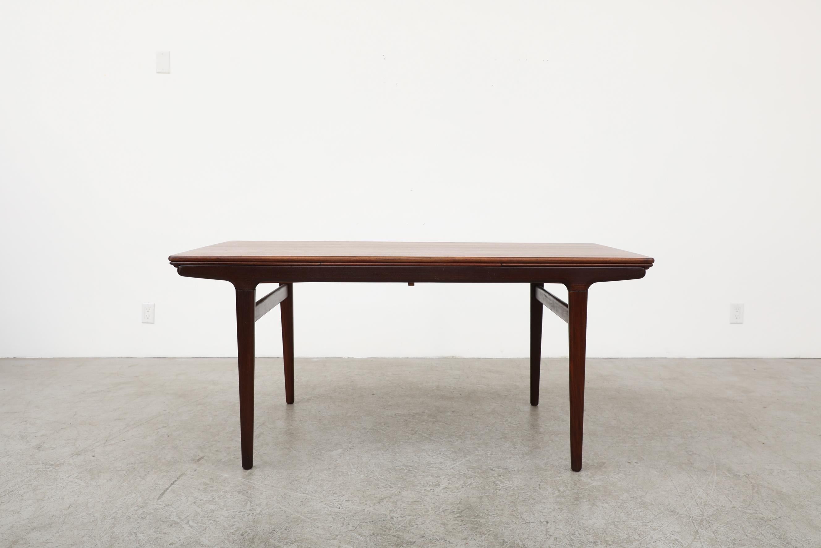 Danish teak dining table with two extension leaves designed by Johannes Andersen for Uldum Mobelfabrik. The table has been lightly refinished with some remaining wear, including light scratches and thin veneer in spots. With leaves it measures