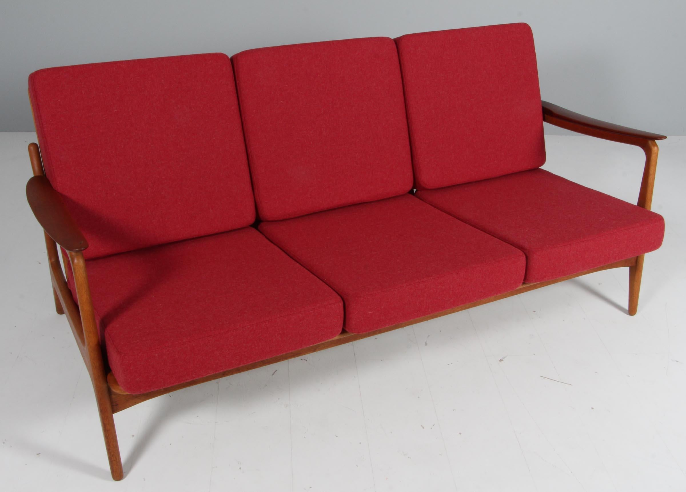Johannes Andersen three seat sofa with frame of oak and armrests of teak.

New upholstered with red 100% New Zealand wool.

Made by Vamo.