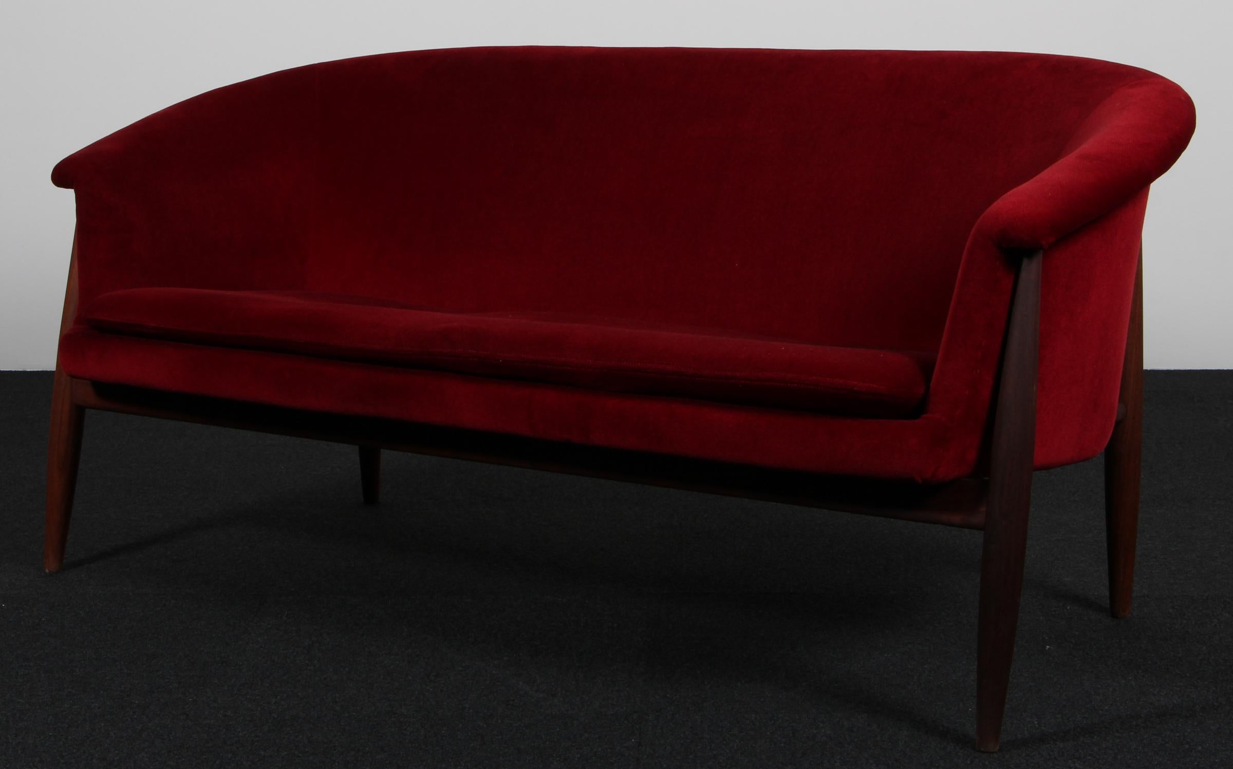 Canapé deux places Johannes Andersen avec structure en teck.

Tapissé de velours rouge profond.

Fabriqué par Trensum.