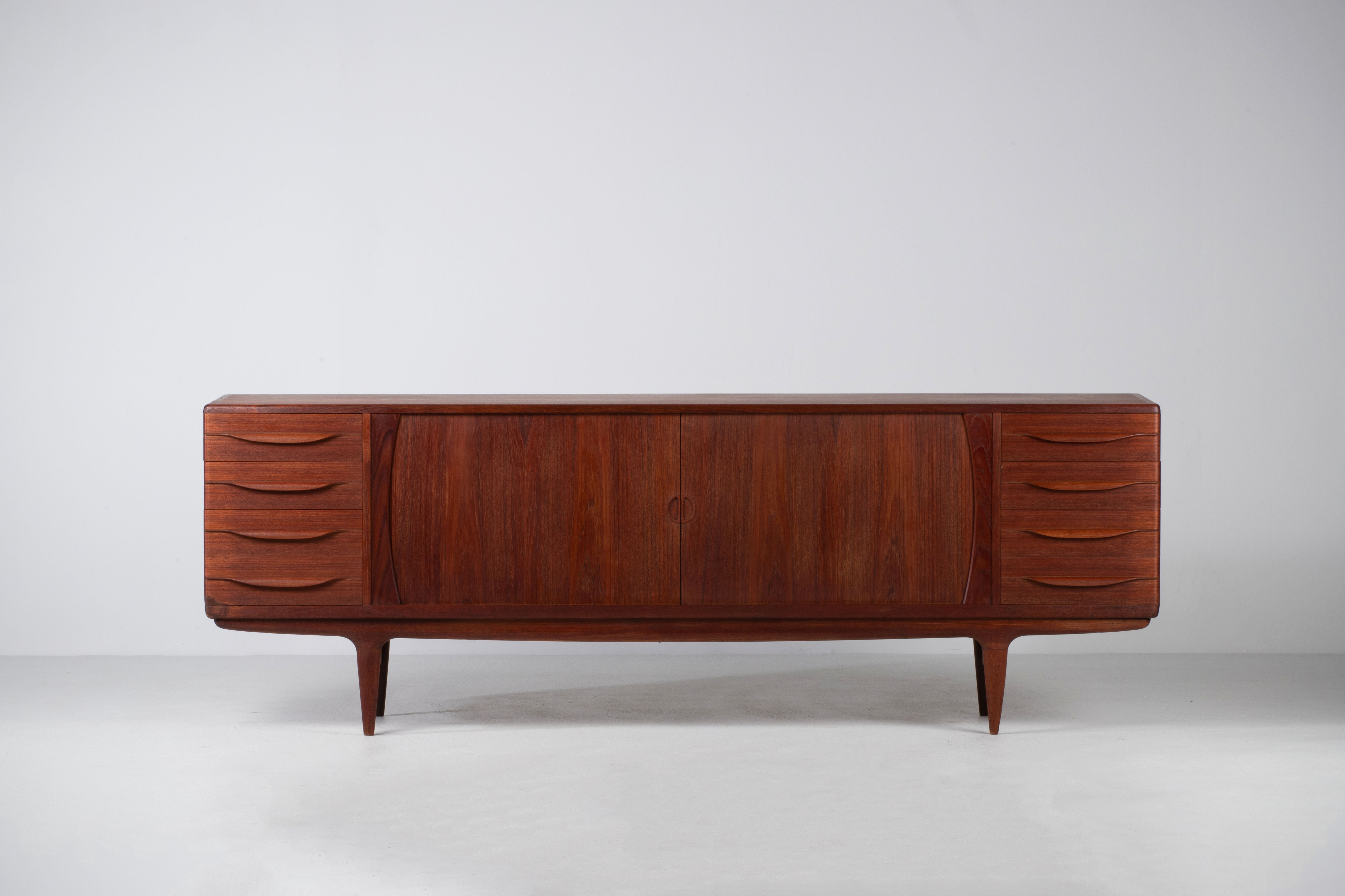 Sublime Danish teak sideboard by the famous designer Johannes Andersen for SAMCOM.
Composed of two times four drawers on the sides and two large curtain doors which open onto 4 height-adjustable shelves.
Good quality of manufacture and finish. A