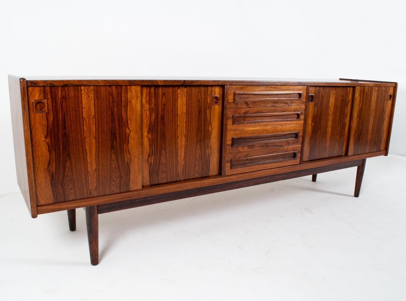 Questa credenza è realizzata con splendidi pezzi di palissandro massiccio, come dimostrano le bellissime venature naturali del legno e il peso robusto dell'intero pezzo. Il design è stato attribuito a Johannes Andersen, noto per le sue silhouette