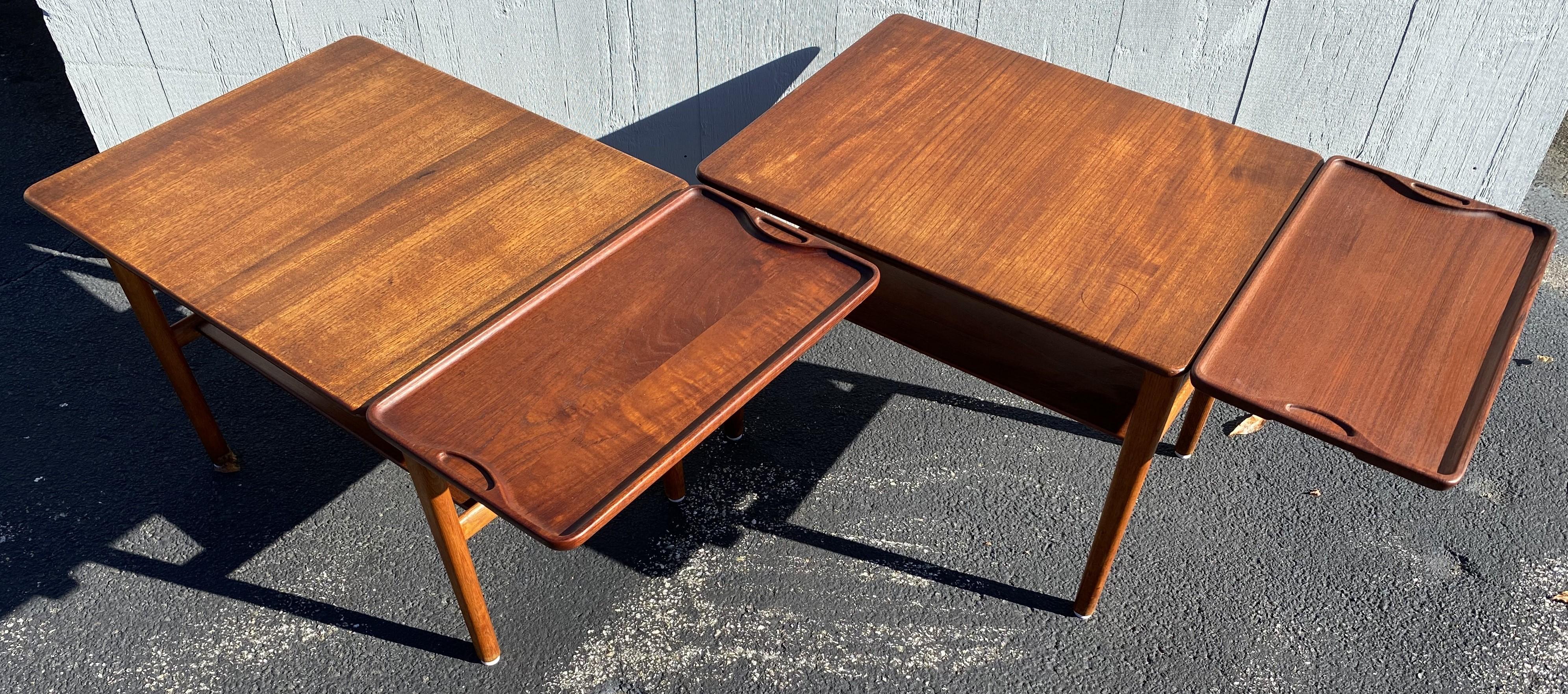 A fine pair of Mid Century modern rectangular teak tables with hidden slide-out trays designed by Hans Wegner and produced by Johannes Hansen, Copenhagen, Denmark, circa 1960. Each table has a slide out hidden shelf under the top with a removeable