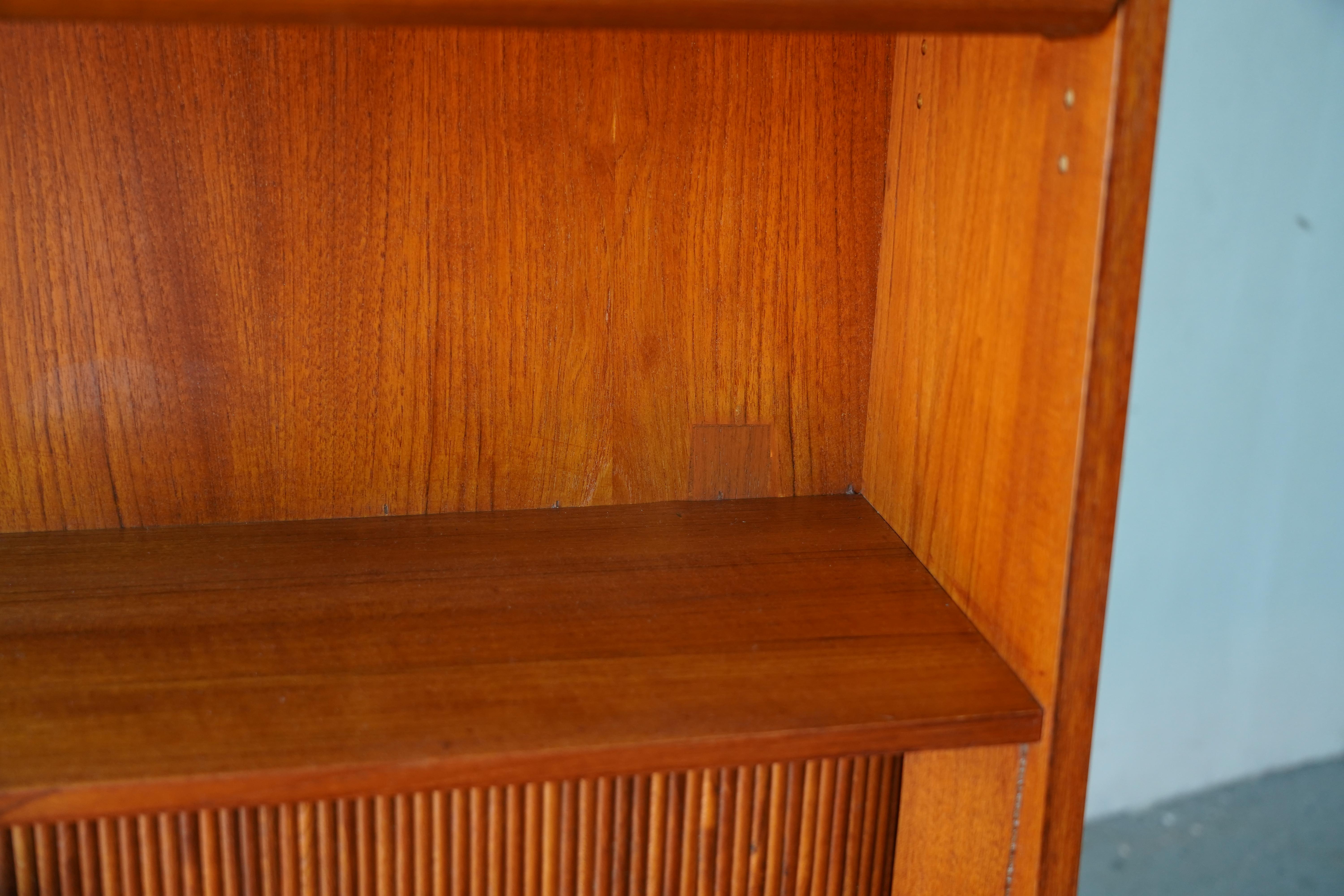 Mid-Century Danish Modern Tall Teak Bookcase and Secretary Desk by Designer Johannes Sorth. This elegant piece features two upper book Adjustable shelves with central tambour doors that reveal three small drawers with an organizer. It also includes