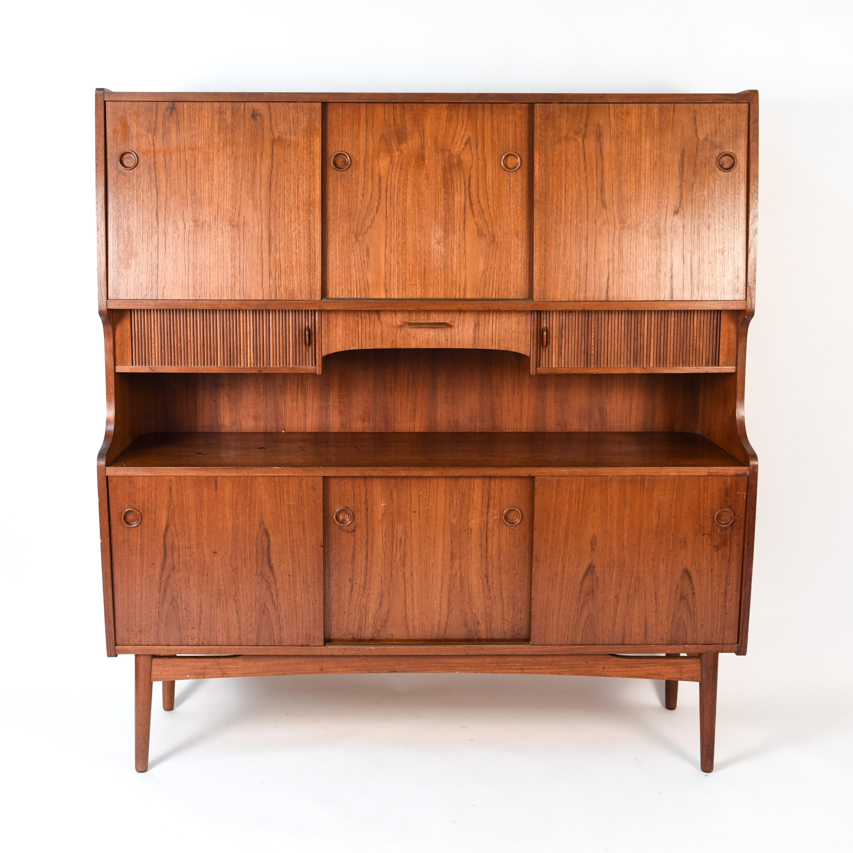 This Danish midcentury highboard is a bold statement piece designed by Johannes Sorth for Nexo Mobelfabrik. This highboard features multiple cabinet areas enclosed by sliding doors with circular recessed handles, as well as smaller compartments with