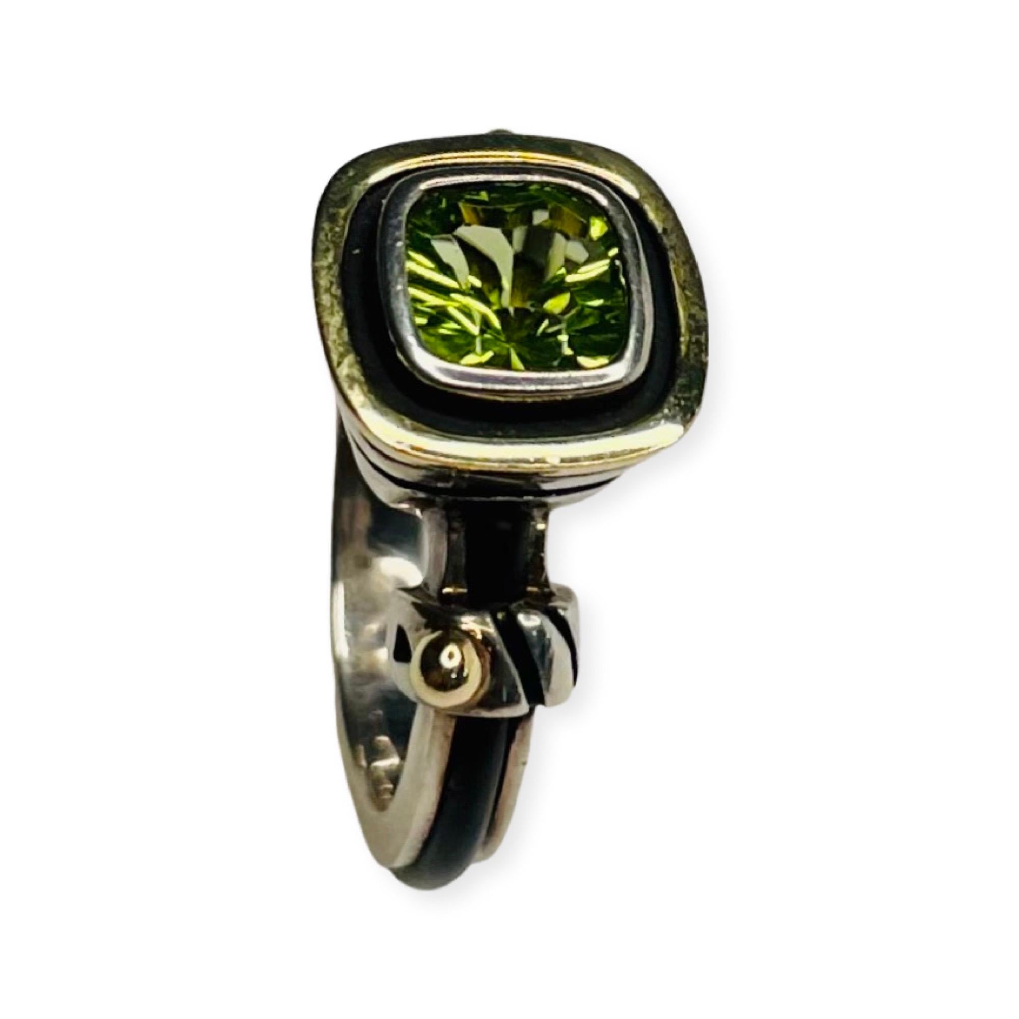 John Atencio 18KY gold and Sterling Silver Peridot Ring. The Hallmarks are 18K and 925. The trademark is JA. The peridot measures 11.0 mm and is set in an 18K yellow gold bezel. The ring is size 6.25.  It can be sized for an additional fee. There is