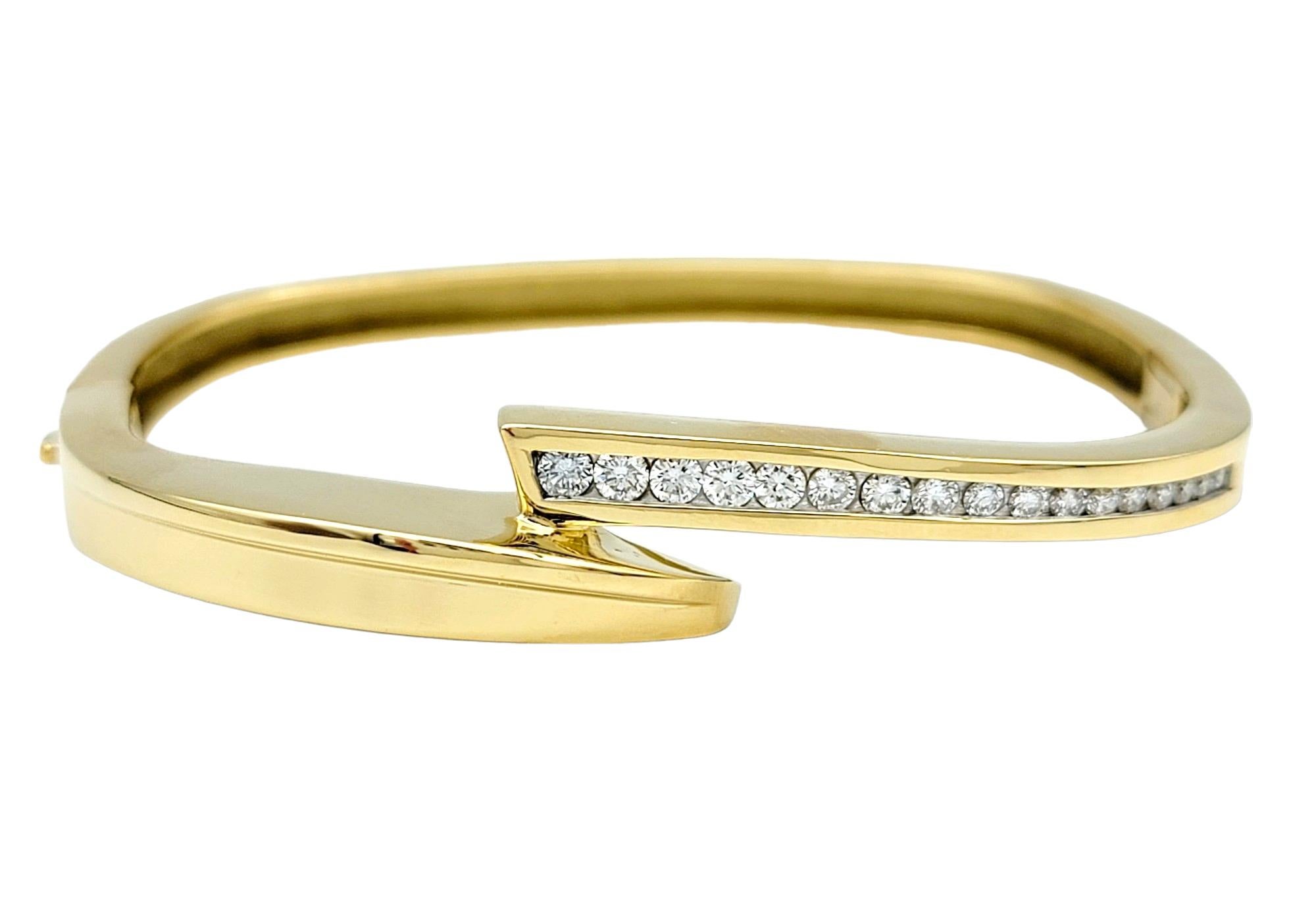 This 18 karat yellow gold bracelet, a creation by the esteemed artisan John Atencio, epitomizes contemporary elegance with its squared bangle and distinctive bypass design. The bypass style, characterized by a crossover or overlapping motif, imparts