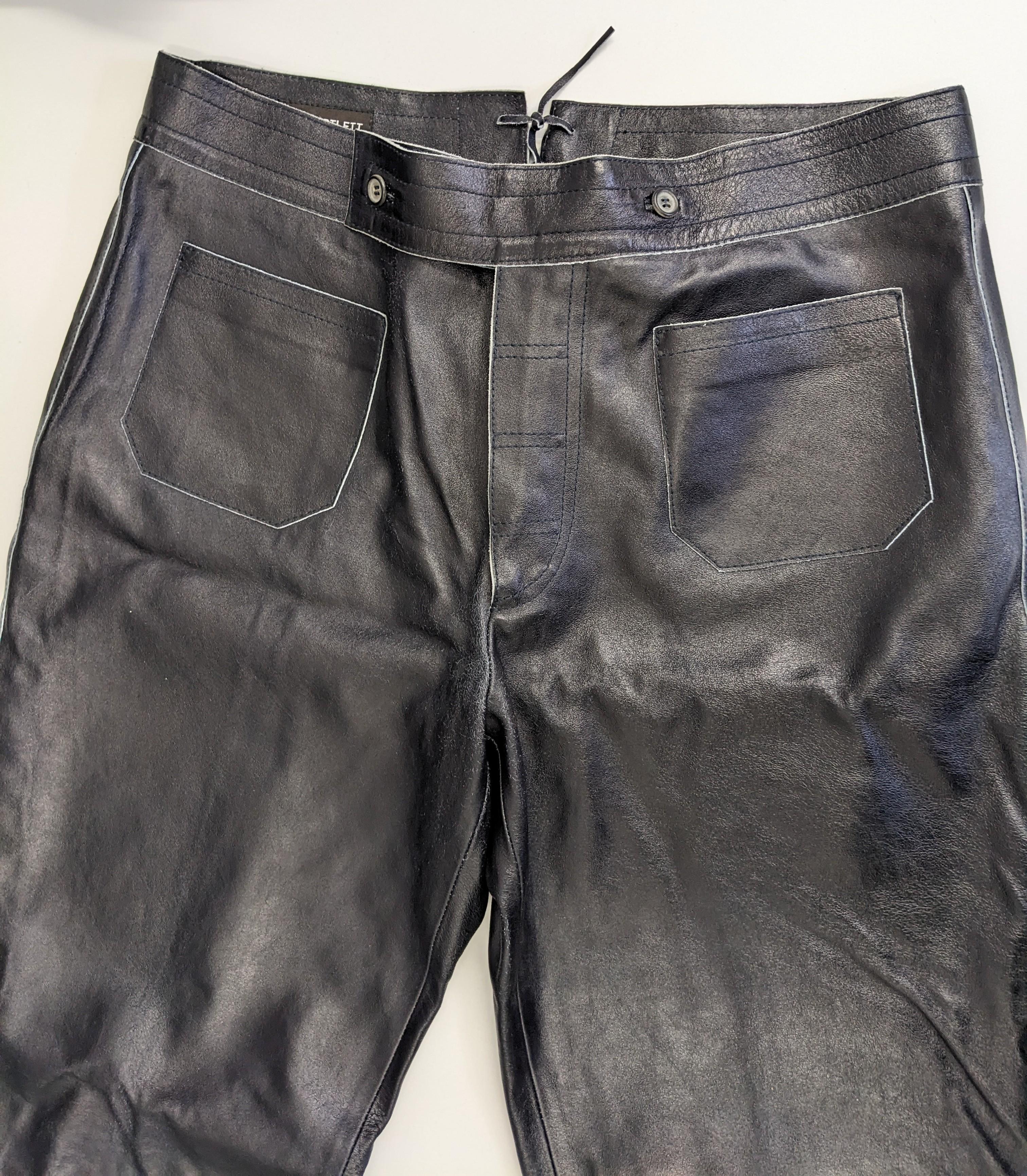 Cool John Bartlett Mens Leather Jeans from the early 2000's. Inky eggplant blue black heavy leather is styled as 1970's jeans with low waist, patch pockets and wide legs. 
Leather is coated and is white underneath, these pants are design to crease,