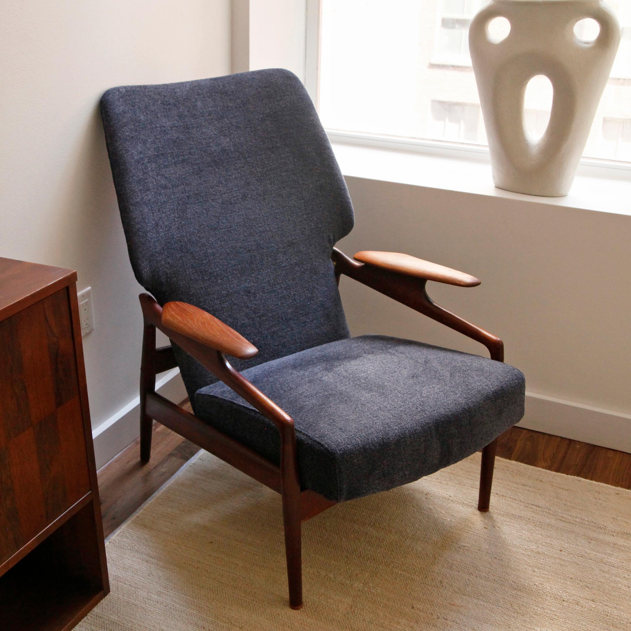This 1960s teak lounge chair by the Danish designer John Boné for Advance Design. Reupholstered in a deep navy bouclé, the wingback chair is a statement sitting on a solid teak sculpted frame. The chair adjusts manually into 3 different positions to