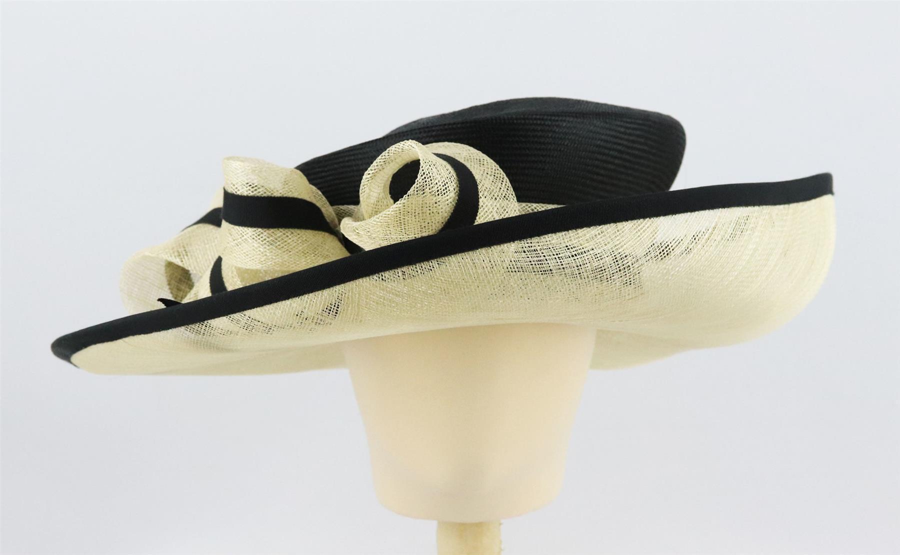This hat by John Boyd is made from black and cream sinamay straw in a structured sweeping silhouette and finished with a bow detail along the front. Black and cream straw. Slips on. 100% straw. Comes with box. Dimensions: H 5 x W 17.4 inches.