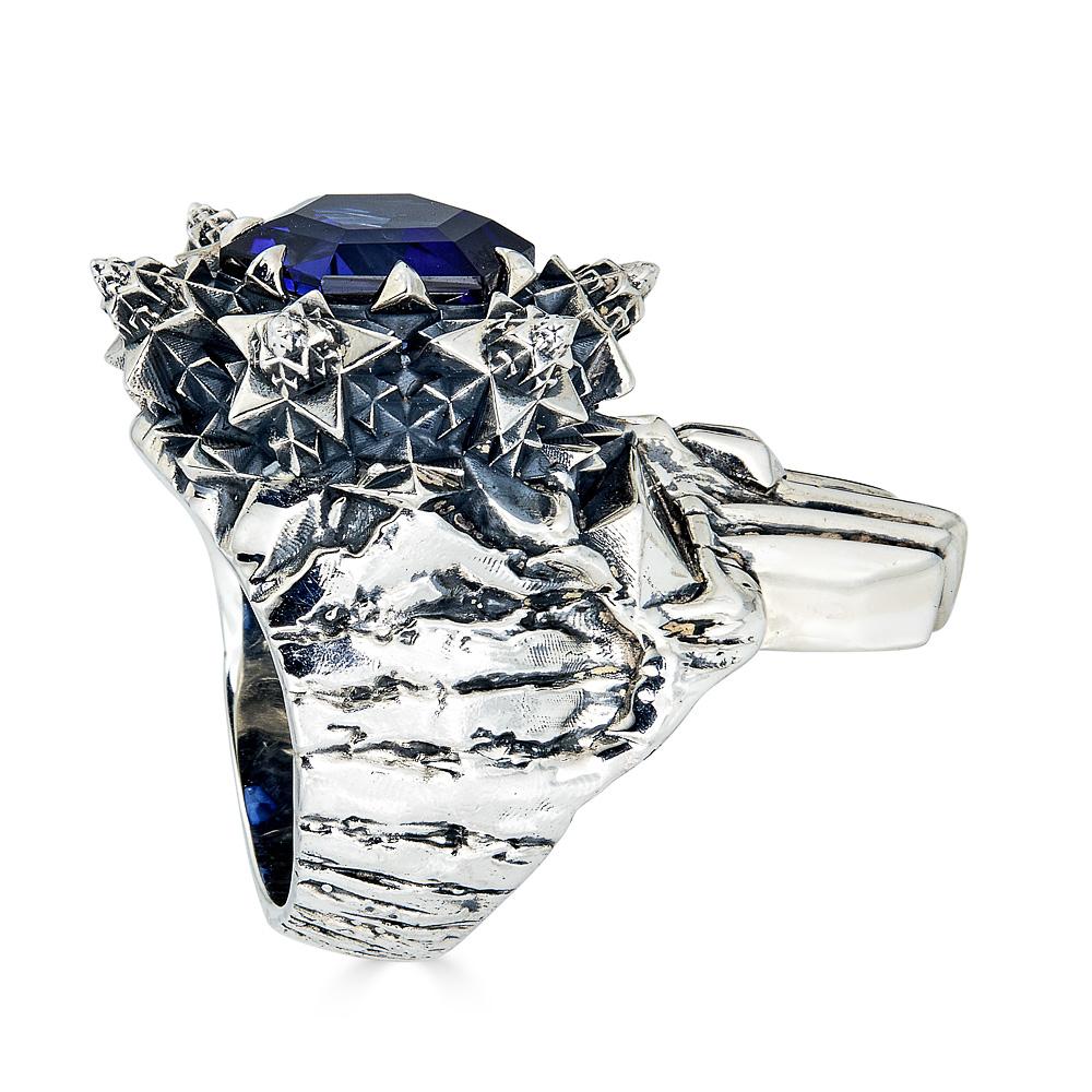 Dieser Totenkopf-Ring in limitierter Auflage ist ein starkes Statement. Dieser kantige Ring mit einem 5-karätigen blauen Saphir, der in Sterlingsilber gefasst ist, spiegelt die natürliche Geometrie wider und verleiht der Trägerin Stärke. Unter