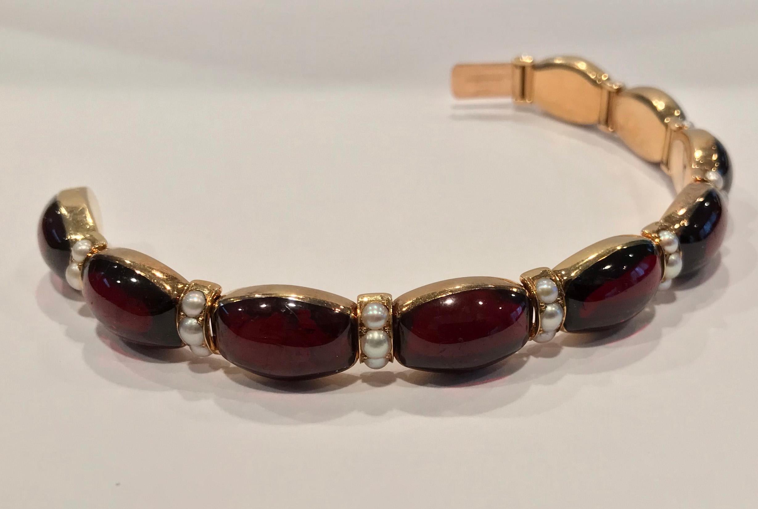 John Brogden Signed Gold Carbuncle and Pearl Bracelet, C.1855. The bracelet is formed of nine bezel set oval shaped cabochon garnets each interspaced with articulated sections of pearls, three in each, total of twenty seven.  terminating with