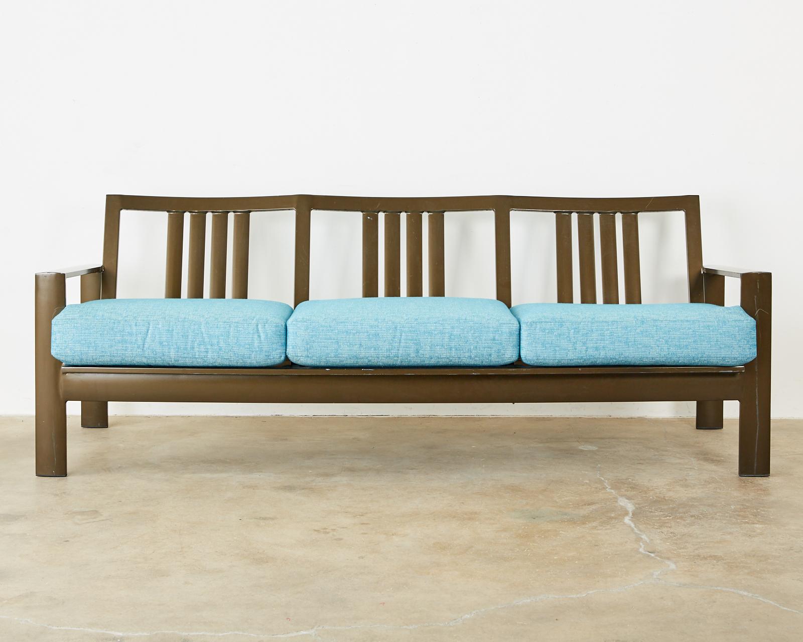 Luxurious wrought aluminum patio and garden sofas designed by John Caldwell for Brown Jordan known as the Parkway cushion sofa with a sleek profile and stylish bronzed finish. Topped with colorful teal plush all weather cushions. The generous