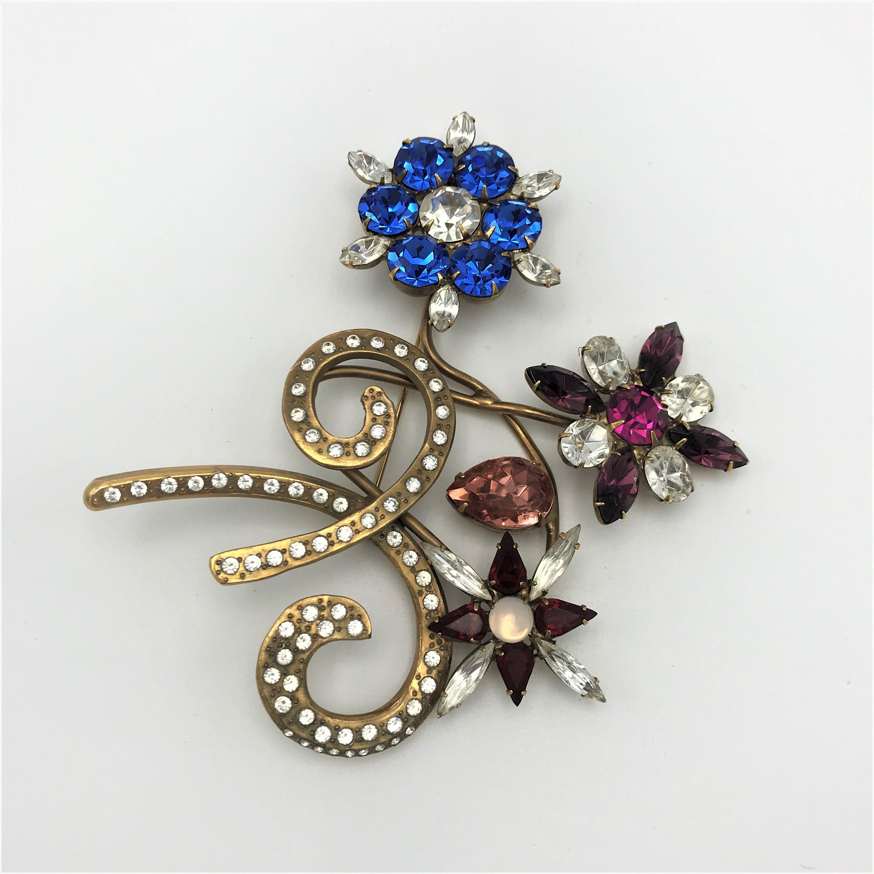 Magnificent John Catalano great brooch with three different rhinestones flowers in shape and color. A bow set with rhinestones holds the flowers, and be worn in different directions. The brooch is signed CATALANO  and gold plated. A vintage