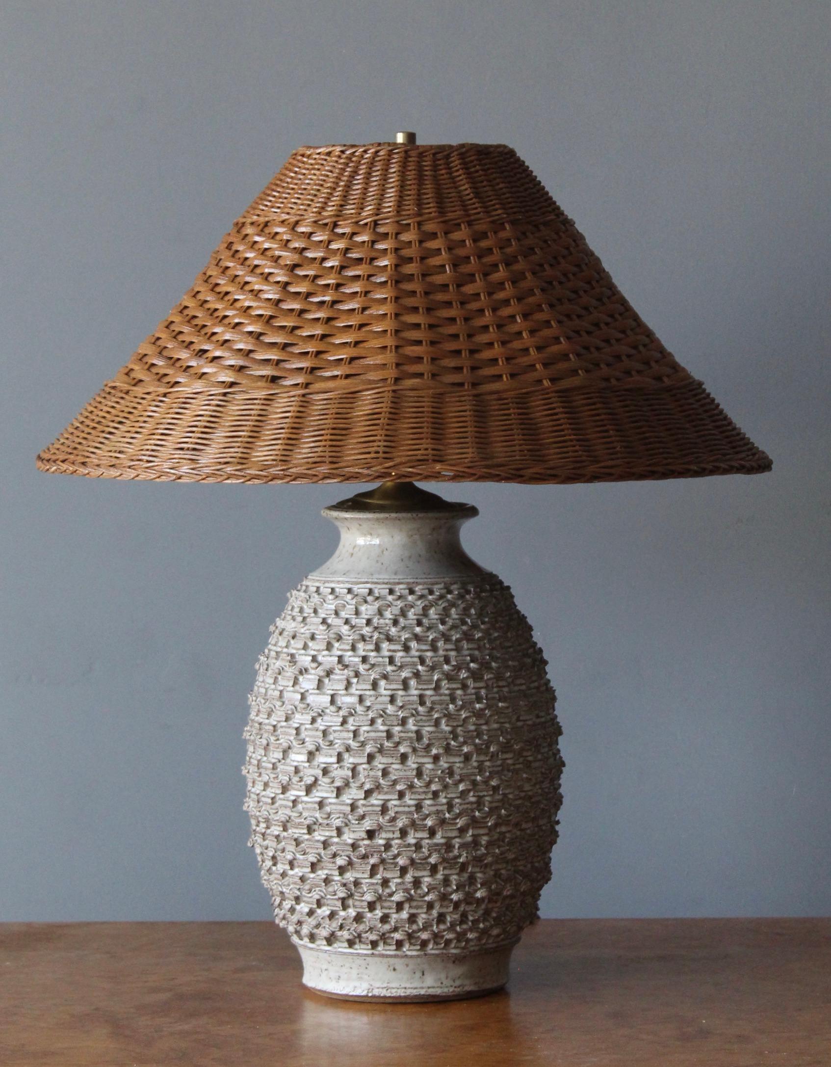 A sizable table lamp in ceramic. Designed by John Coiner and produced Artists Studio, United States, 1977. Form is enhanced by incised artistic details. Signed and dated. Assorted rattan lampshade.

Dimensions include lampshade.