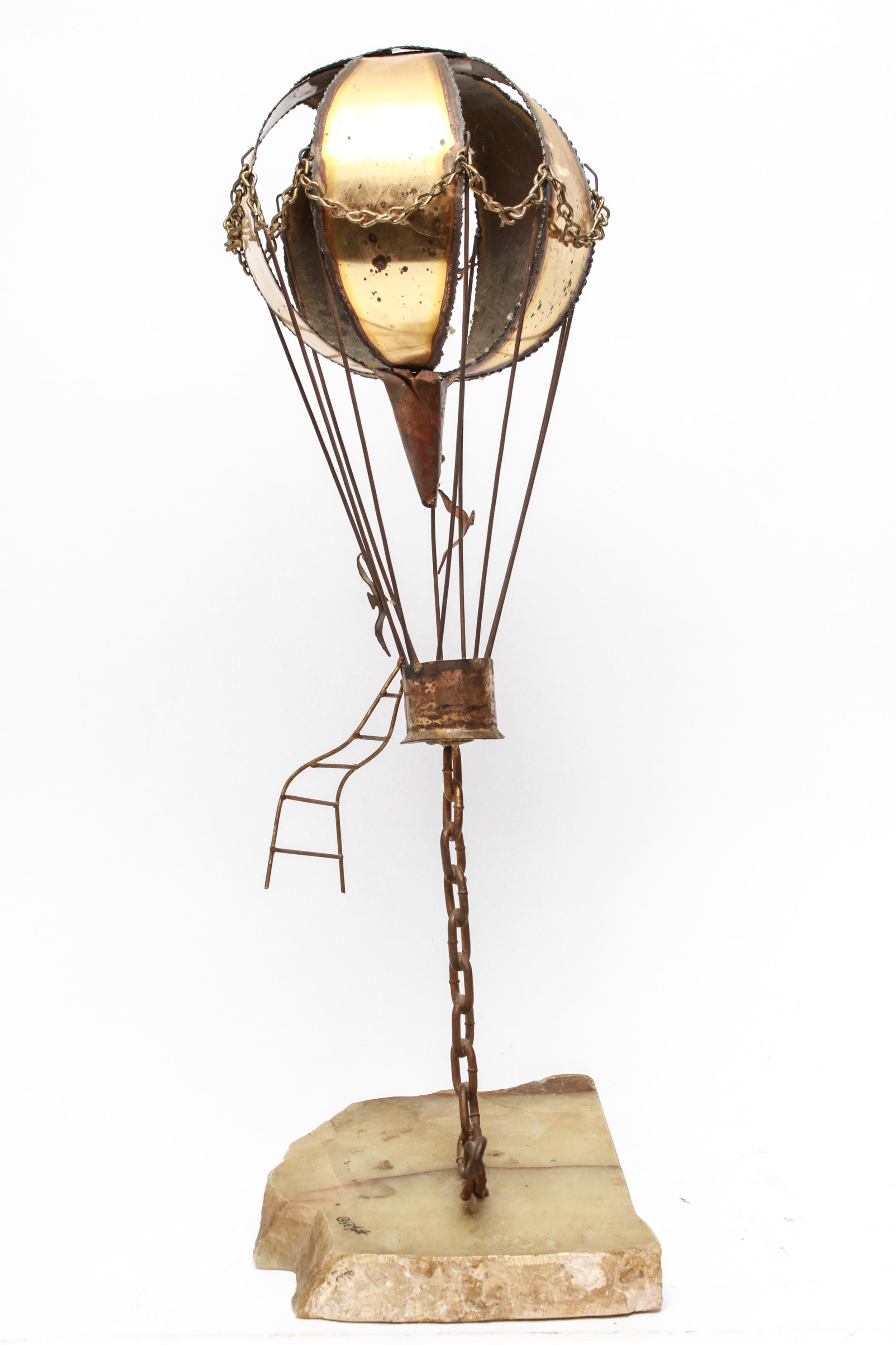 American Brutalist brass hot air balloon sculpture designed by John Demott (American, 20th century) during the 1970s, mounted on a slab of polished onyx and signed in one corner 
