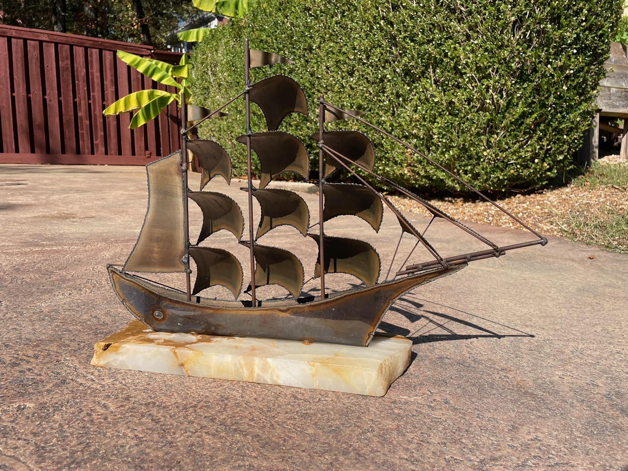 Sculpture en métal découpé au chalumeau de John Demott, datant du milieu du siècle dernier. Le clipper de style brutaliste a des couleurs or, cuivre et bronze pour le métal. La base en pierre semble être en onyx. La signature de Demott est présente