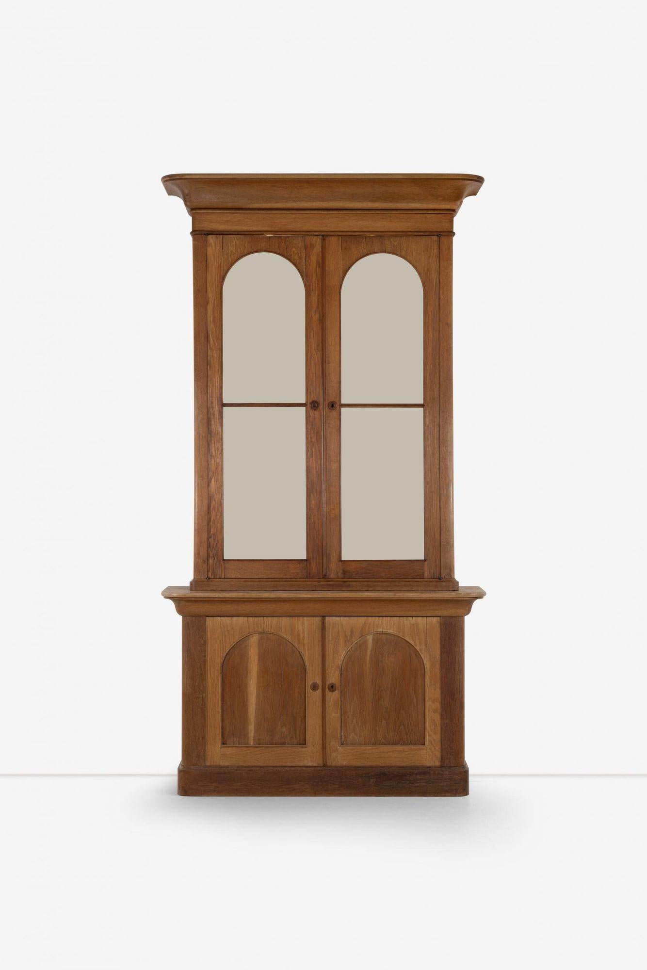 John Dickinson Monumentalschrank für das Historic Firehouse, San Francisco 1970: Der Schrank ist aus Eichenholz und Glas gefertigt und besteht aus zwei Teilen; der obere Teil hat zwei Glastüren, hinter denen sich ein Regal und zwei dramatische