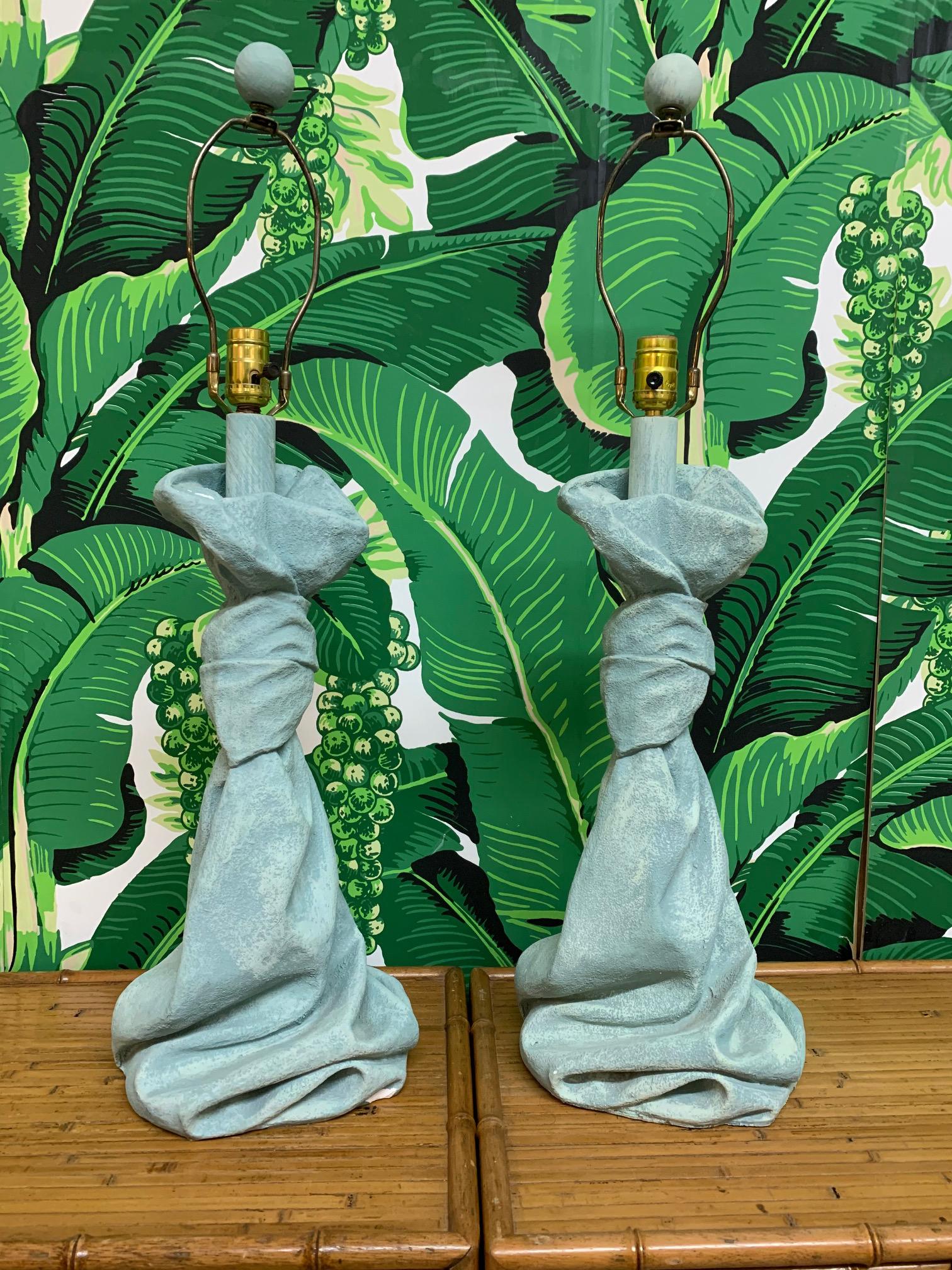 Pair of table lamps in draped fabric motif in the style of John Dickinson. Heavy plaster construction. Good vintage condition with imperfections consistent with age (see photos).
 