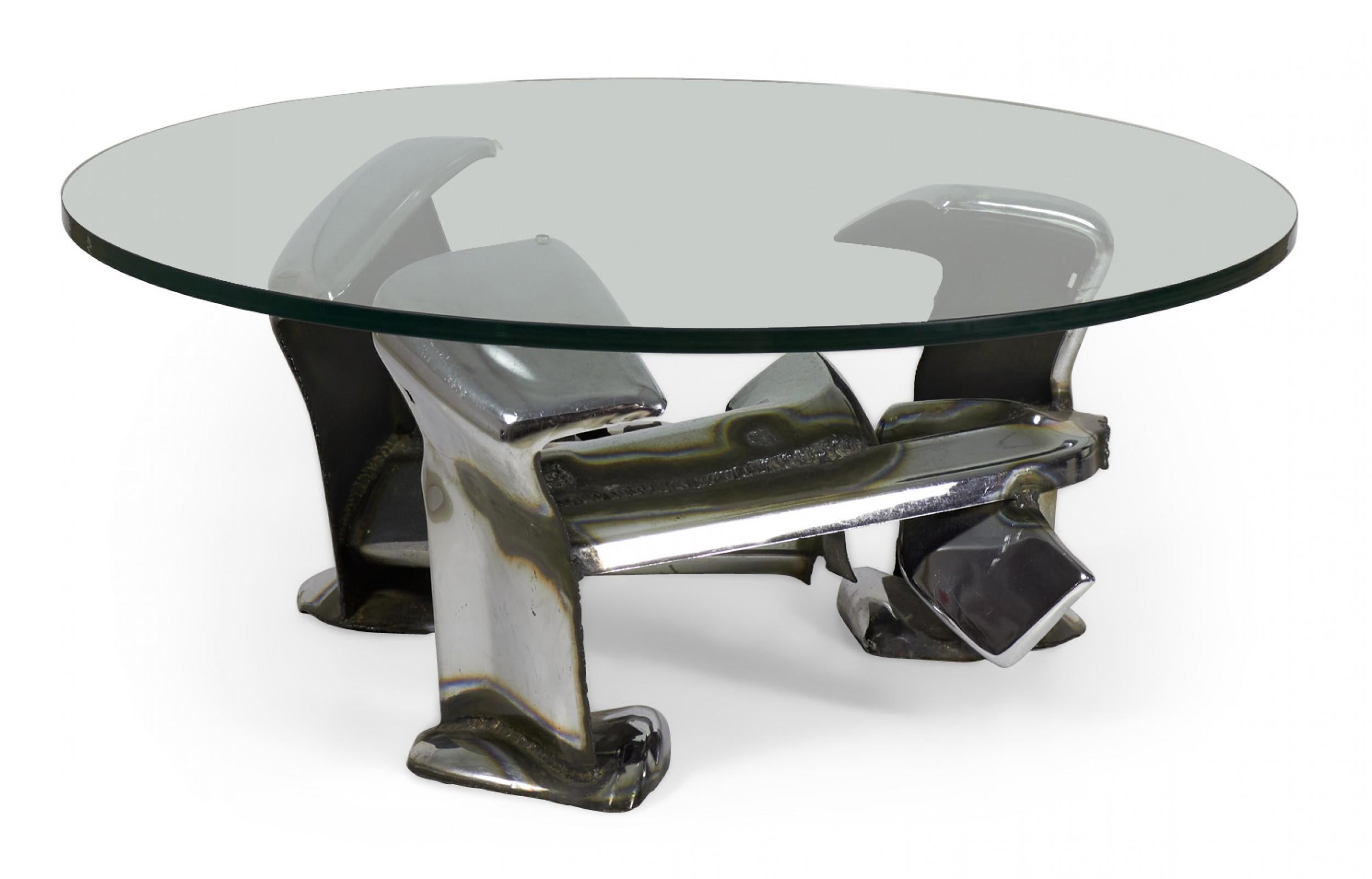 American mid-century Brutalist (1976) sculpted chromium steel coffee table made of welded and shaped car bumpers intertwined to form a base, with a circular clear glass top. (signed, JOHN E. PENDLETON '76)