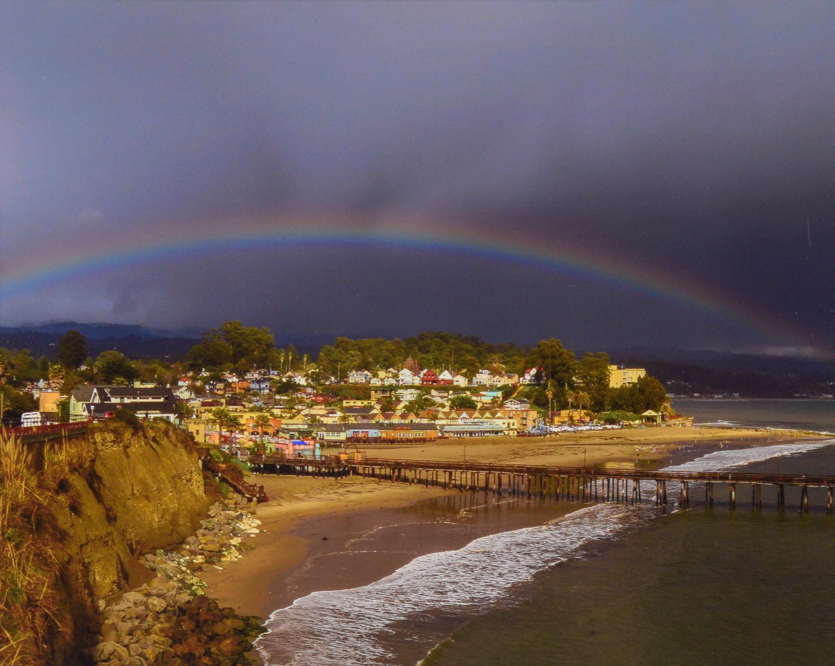 Rainbow Over Capitola Village, Santa Cruz - Colored Photograph

Color photograph of a rainbow shining over Capitola Village in Santa Cruz, California by John F. Hunter (American, 20th C). The viewer looks out onto Capitola beach where the pier is