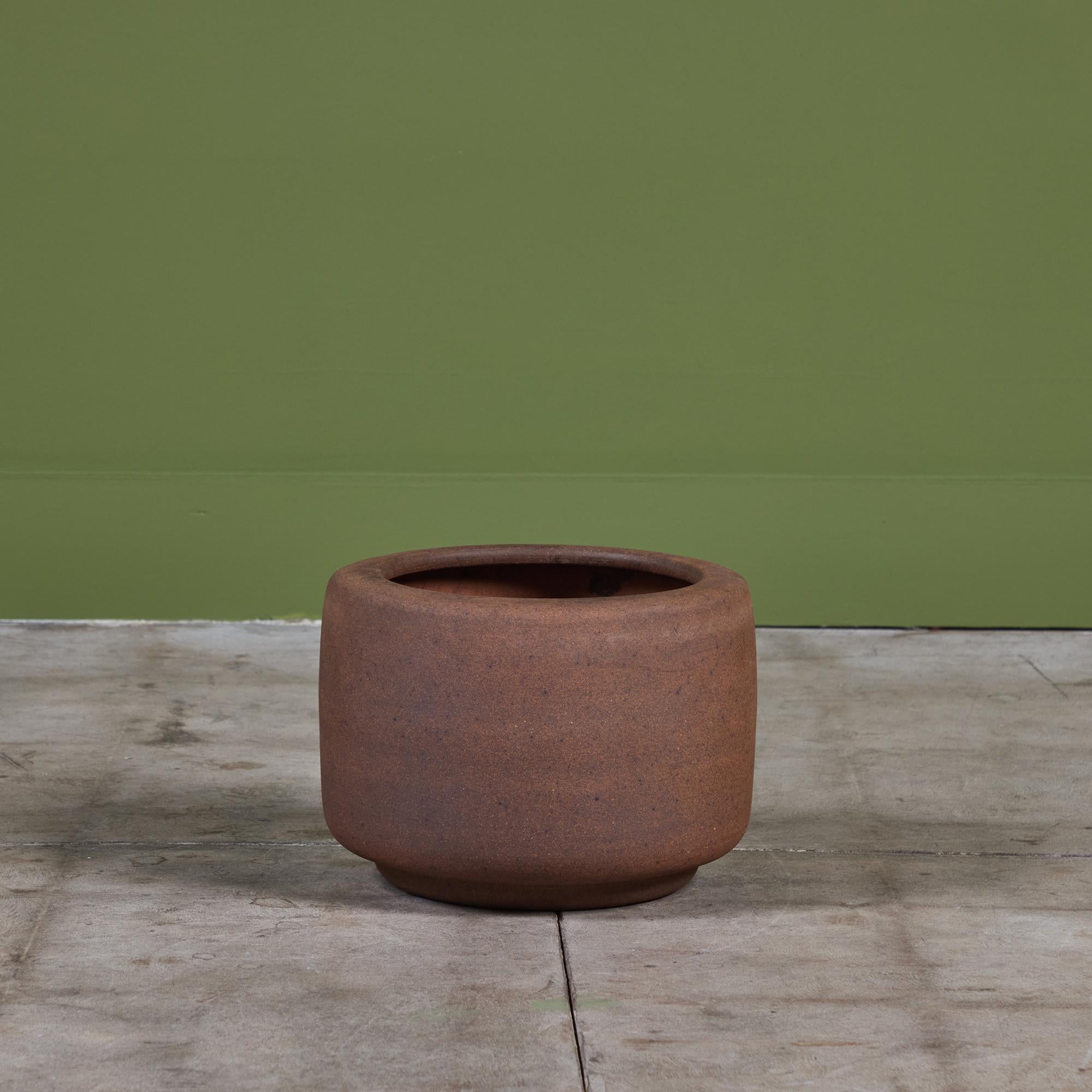 Stoneware planter by John Follis for Architectural Pottery. This example has a drum shape with a rounded lip that curves in at the top of the piece. Planter stamped 