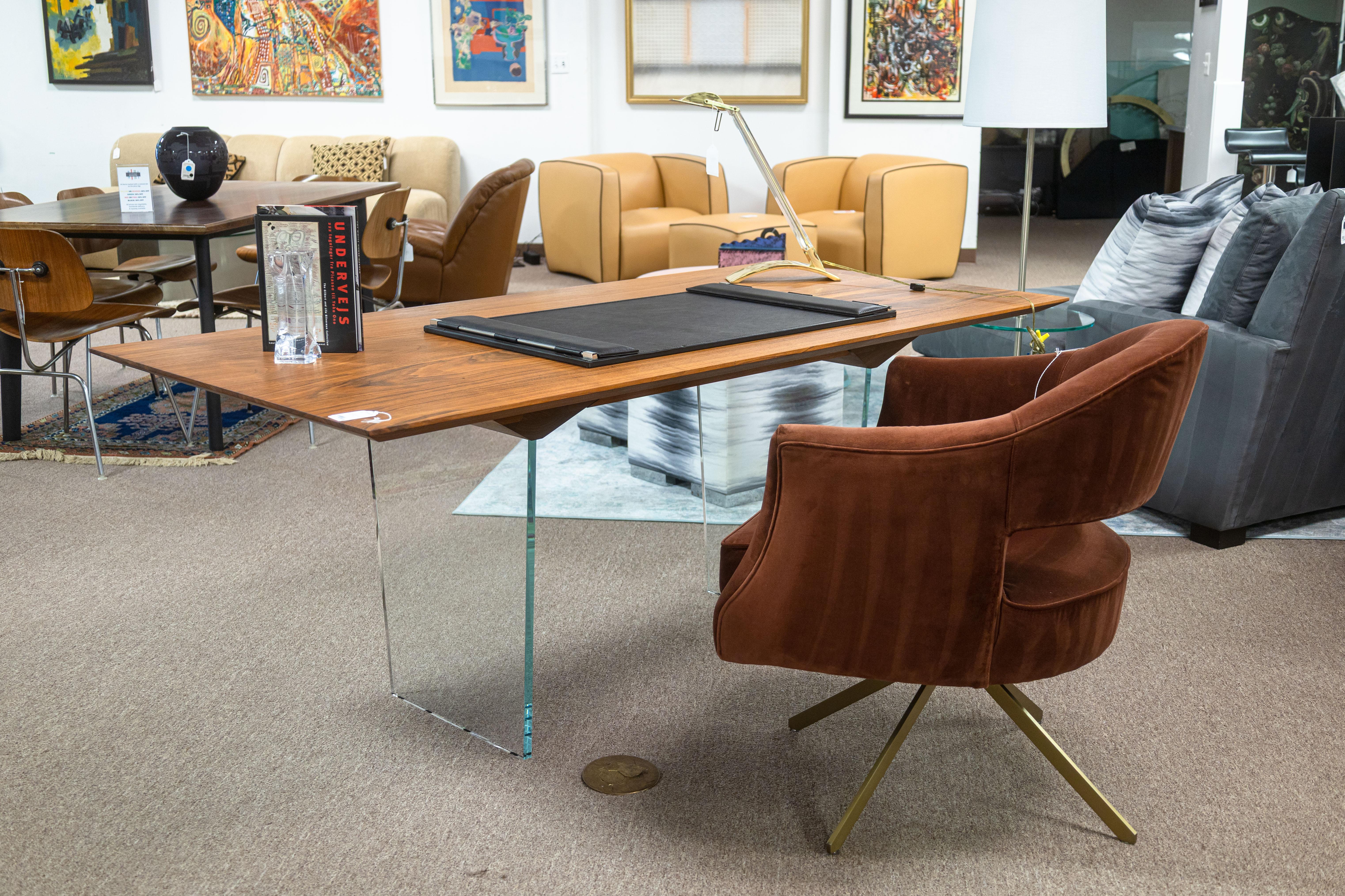 A custom made John Ford office desk. This beautifully crafted contemporary desk features a very sleek, modern design with a large slab wood table top, and two glass support legs. The tabletop has a floating look due to the very clear glass pedestal