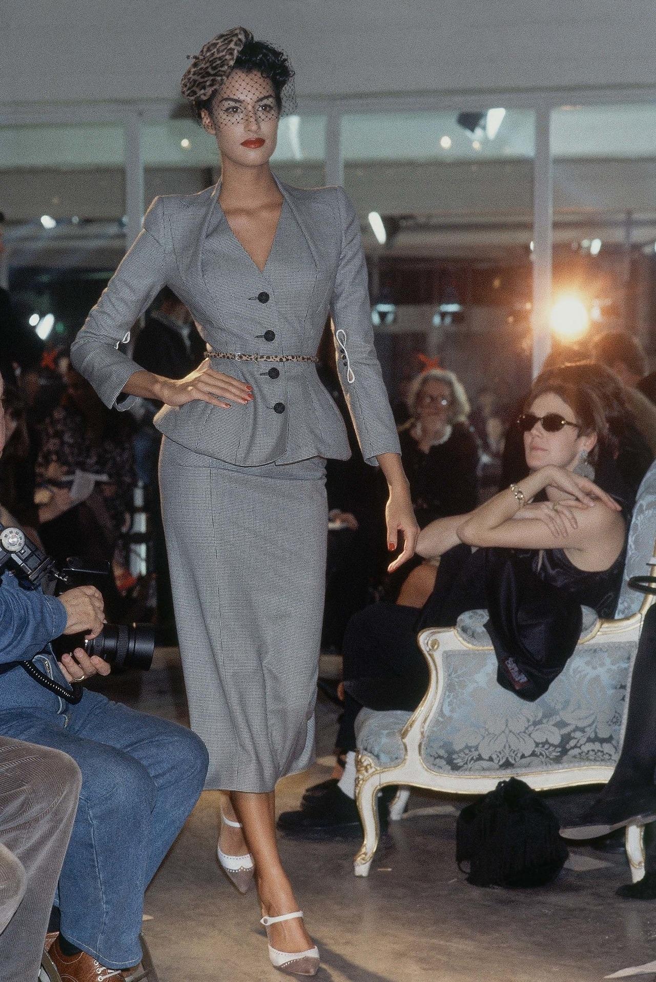 JOHN GALLIANO 1995 Vintage grey houndstooth padded hip jacket/skirt suit 

Houndstooth checked wool skirt suit. Long sleeved jacket with  padded  shoulders. Nipped waist with padded hips. Contour seams to accentuate hourglass silhouette. Halter-neck