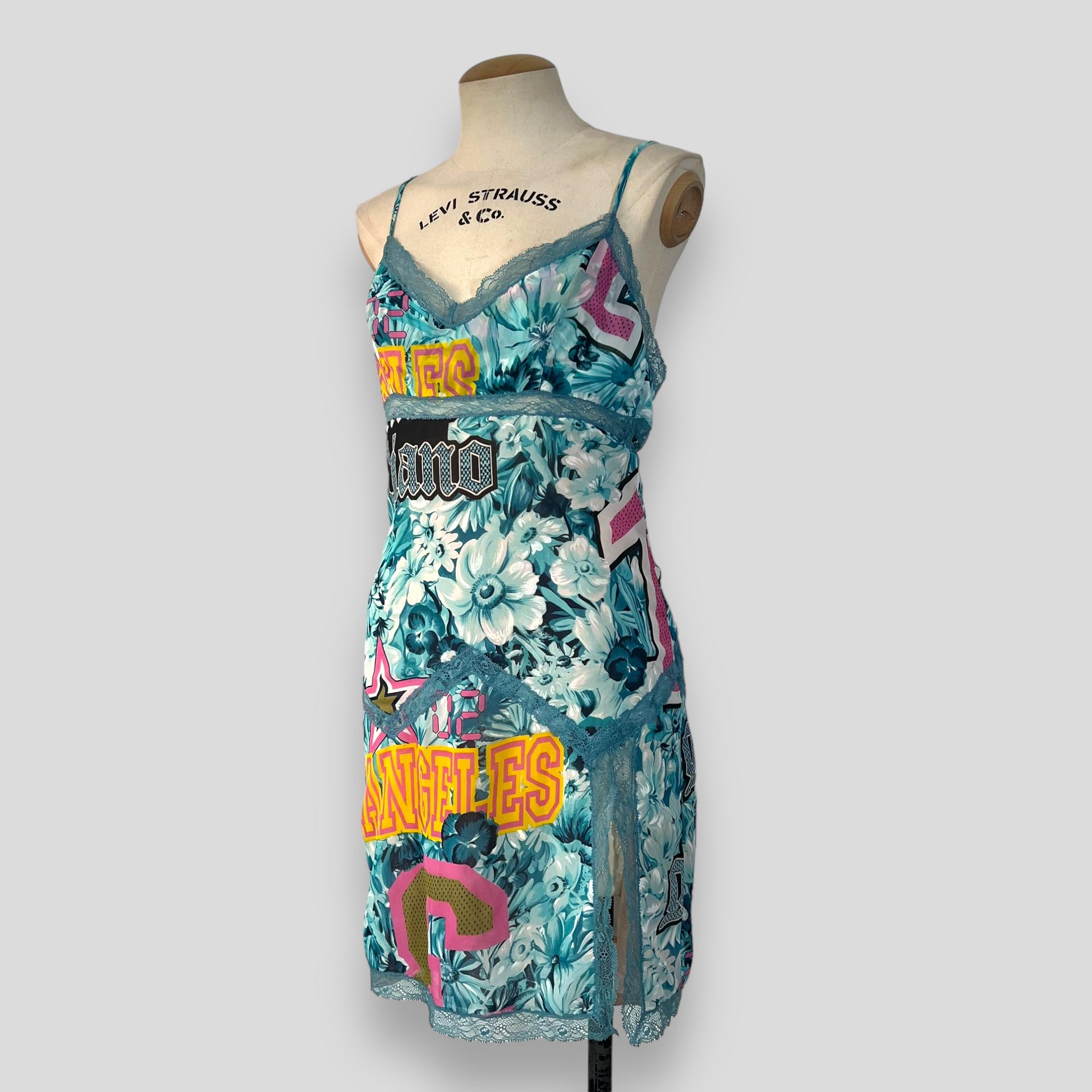

Description: This striking mini dress by John Galliano from the 2000s features a vibrant graphic print that showcases his avant-garde approach to fashion. Designed with intricate floral and lettering motifs, the piece embodies Galliano's signature