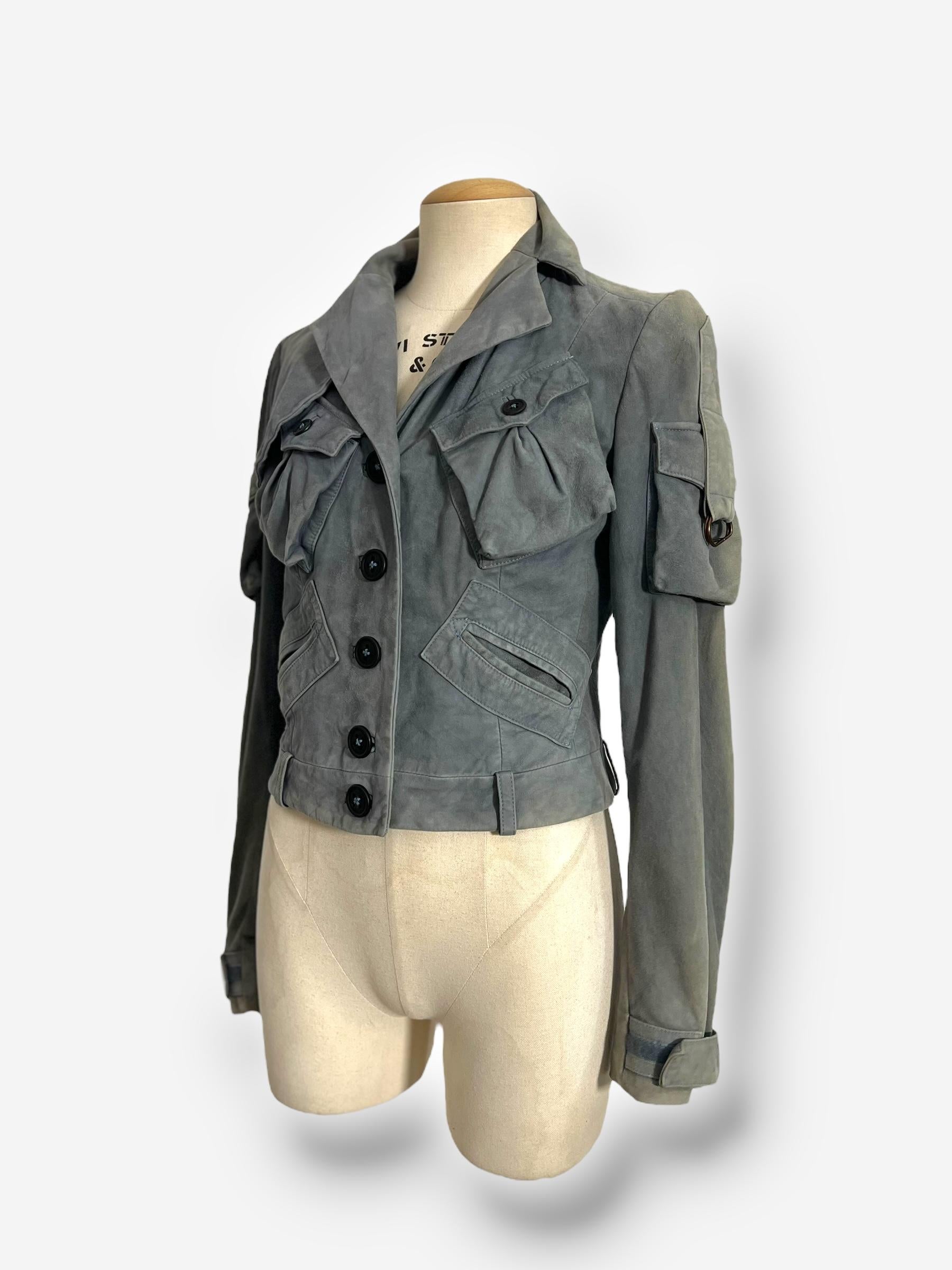 
Ensemble en cuir velours John Galliano de 2003, comprenant une veste structurée de style cargo et un pantalon assorti. La veste est dotée de boutons surdimensionnés, de multiples poches à rabat et de manches extra-longues, évoquant une esthétique à