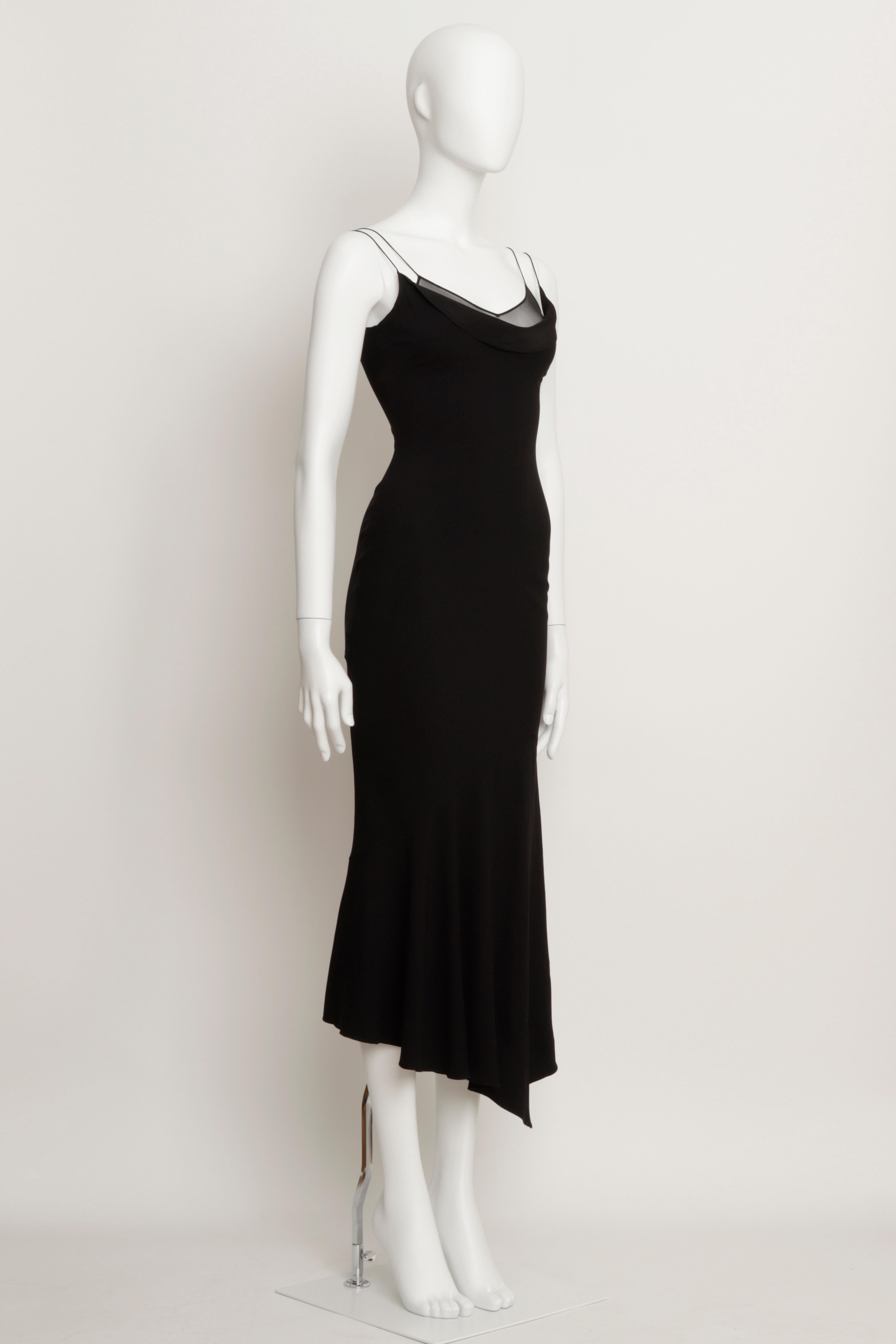 Iconico e intramontabile abito da sera John Galliano in crepe satinato nero con taglio in sbieco della collezione A/I 2000. 
Doppie spalline con scollatura drappeggiata e dettagli in chiffon di seta trasparente. Chiusura con zip nascosta nella