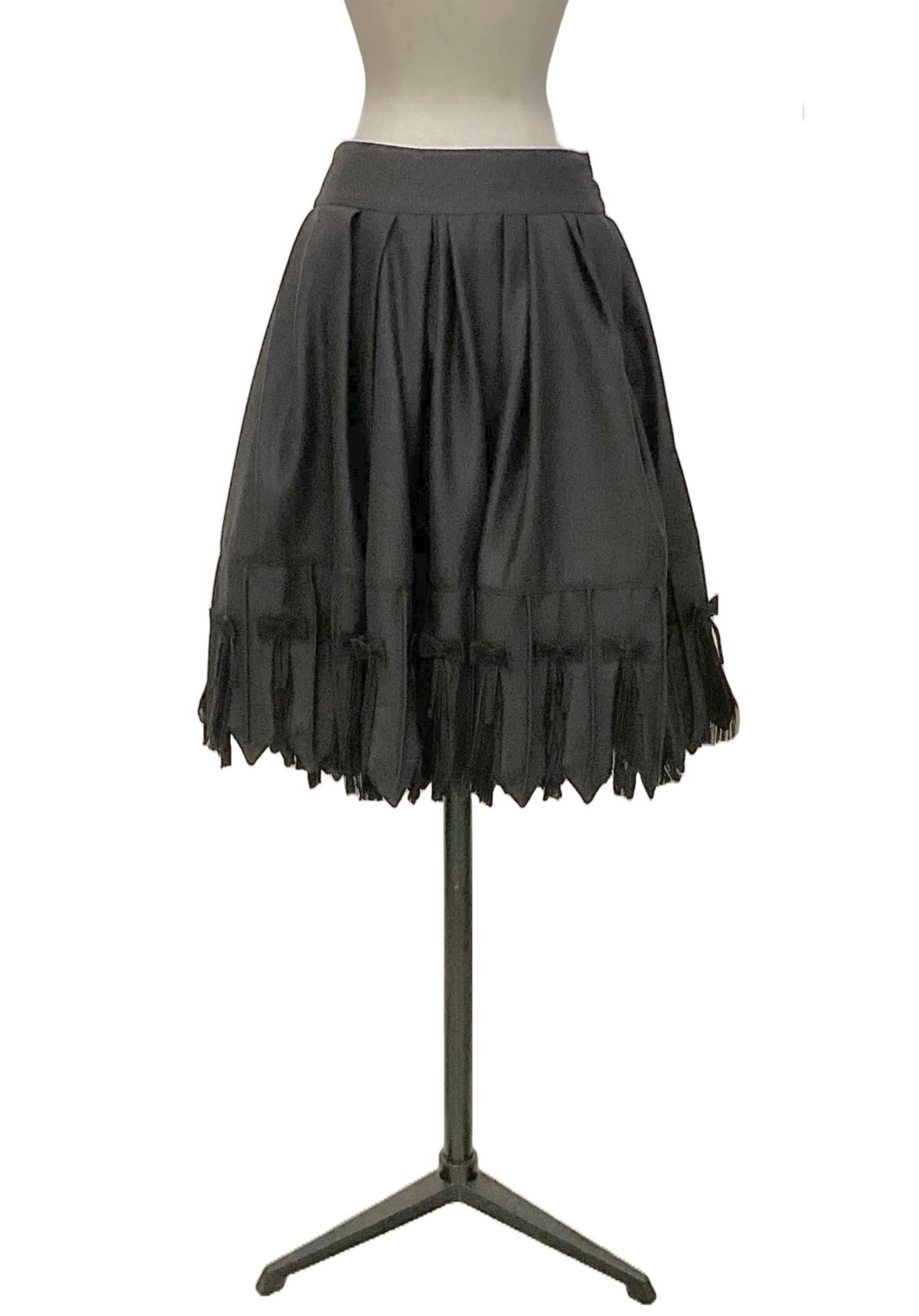 Wide pleated gray flannel skirt from the Ready to
Wear Fall Winter 2010.
Below the basque, on the front side, are two pockets with
flap with decorative flat tablet buttons covered in the same
skirt fabric.
The hem is enlivened by chasing spikes.
The