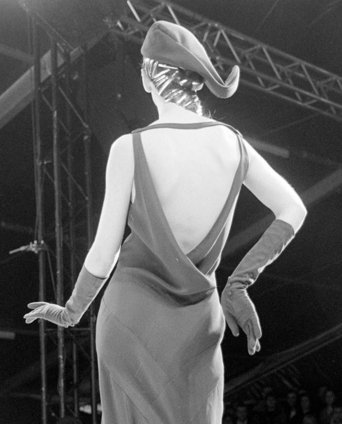 John Galliano Autunno/Inverno 1988 'Hairclips' abito nero in crêpe di viscosa con pannelli a punta, schiena aperta e gonna svasata a godet.

Questa stagione è stata la prima in cui Galliano ha introdotto abiti con taglio sbieco ispirati agli anni