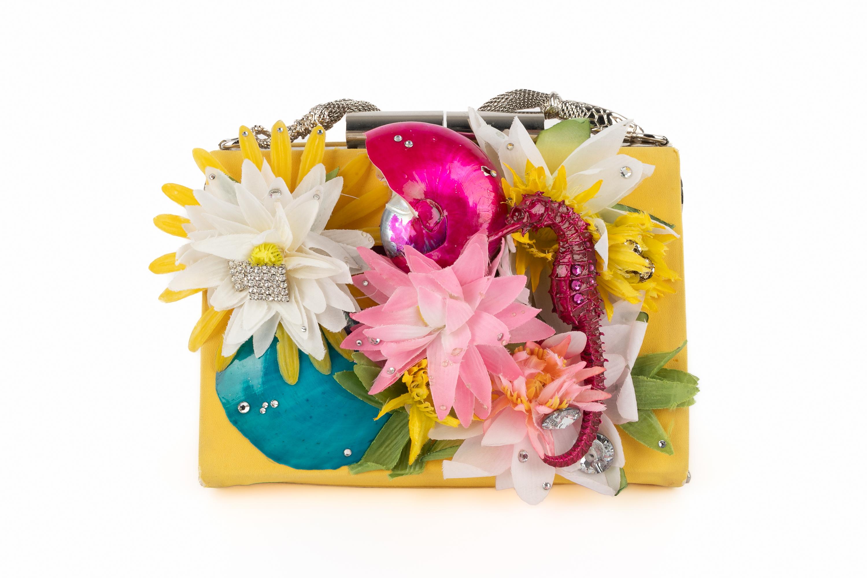 GALLIANO - Sac en soie jaune à double compartiment, décoré de fleurs et de coquillages multicolores. Collectional printemps-été 2005. A noter qu'un obus est endommagé.

Condit :
Bon état

Dimensions :
Longueur : 20 cm - Hauteur : 13 cm - Profondeur
