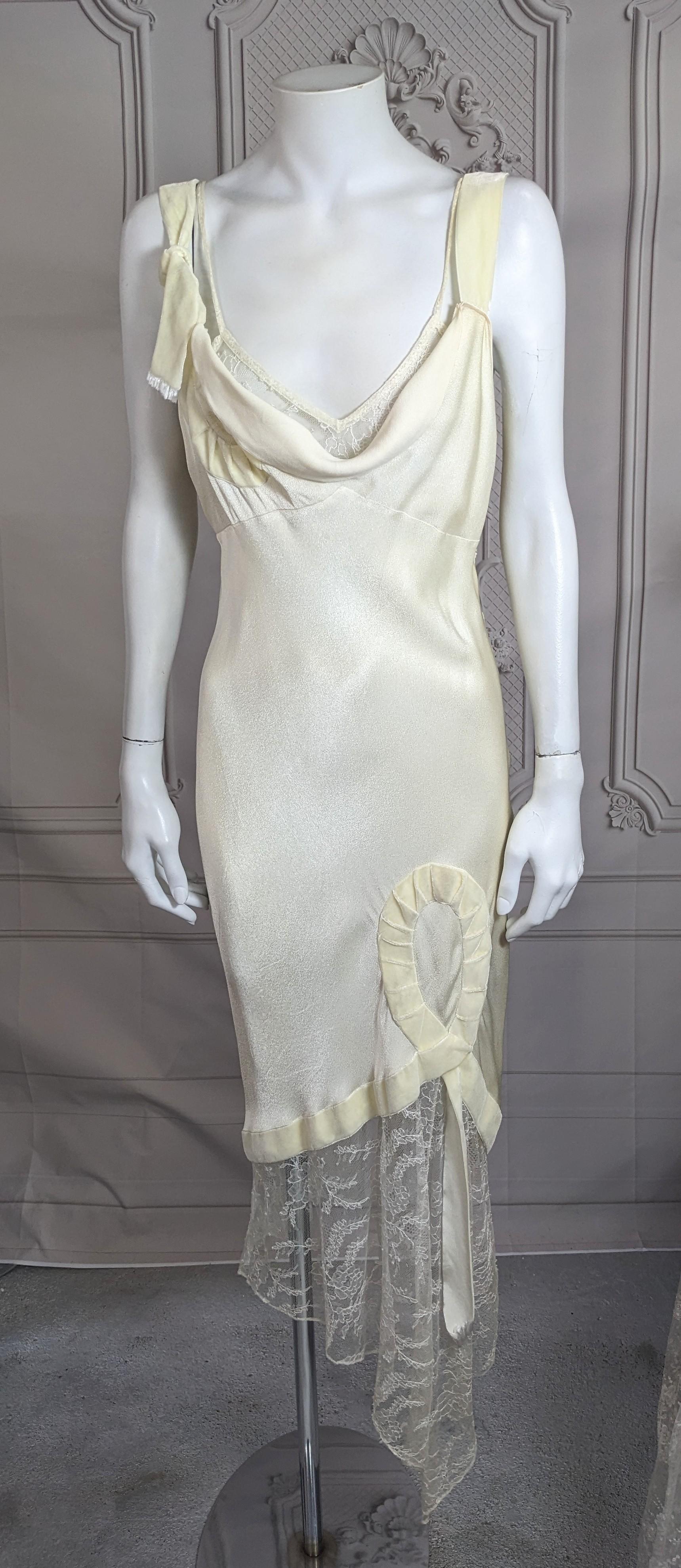 John Galliano Fall/Winter 2001 collection Bias Cut Evening dress of his favorite satin backed crepe. Draped bodice with faux floral lace camisole and knotted ivory velvet ribbon decoration. Ivory-cream satin back crepe with deep floral dipping lace