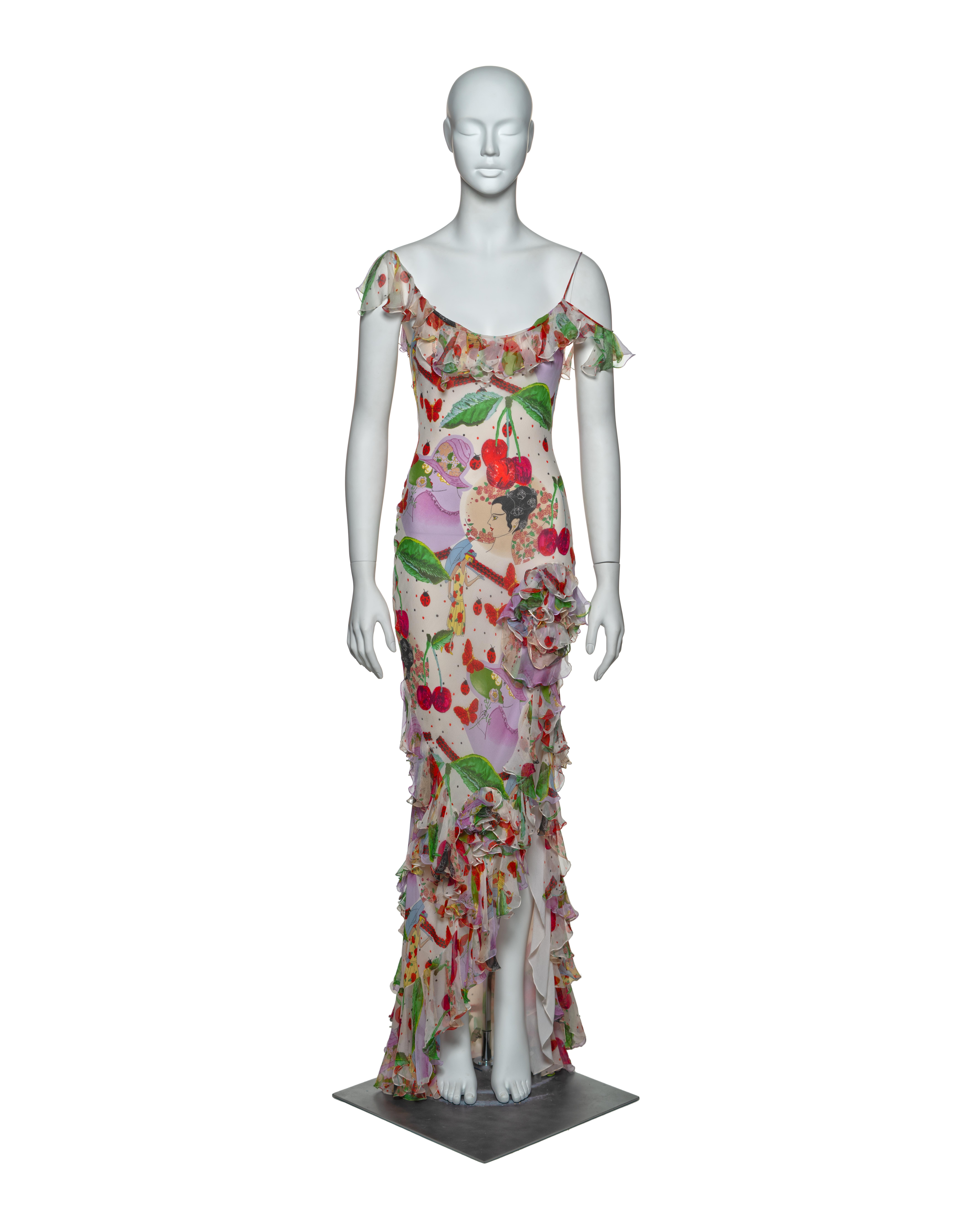 This John Galliano bias-cut silk chiffon dress features a surreal botanical print with cherries, butterflies, and ladybugs on a white background. The off-shoulder neckline is adorned with delicate ruffled chiffon. Two three-dimensional spiral