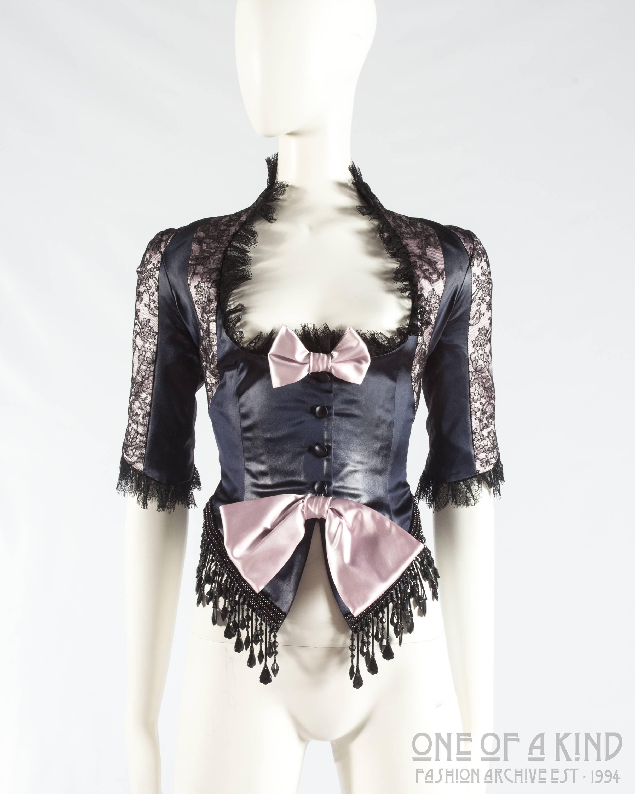 John Galliano black acetate and lace fringed evening jacket

- beaded fringe 
- lace trim 
- button closures 
- low cut neckline 
- two pink decorative bows on front 
- one black velvet decorative bow on back 

Spring-Summer 1994
