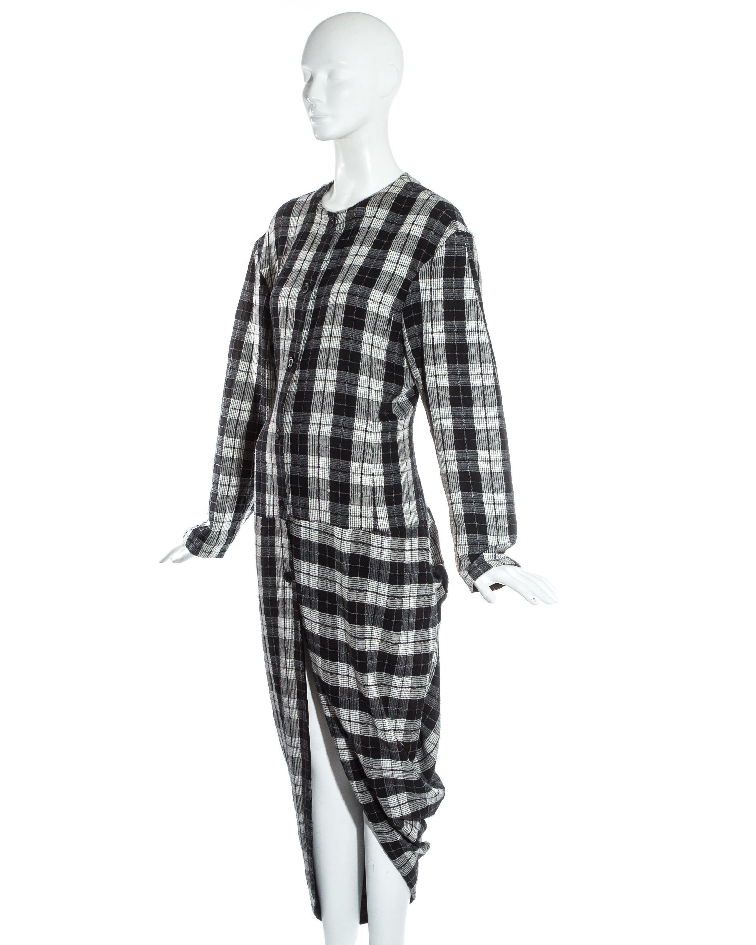 John Galliano; black and white plaid cotton bustled shirt dress. Wide cut shoulders with padding, button fastenings down centre front, draped skirt simulating a bustle, fitted waist and a signature Galliano rolled 'rose' at the hip. 

Fall-Winter