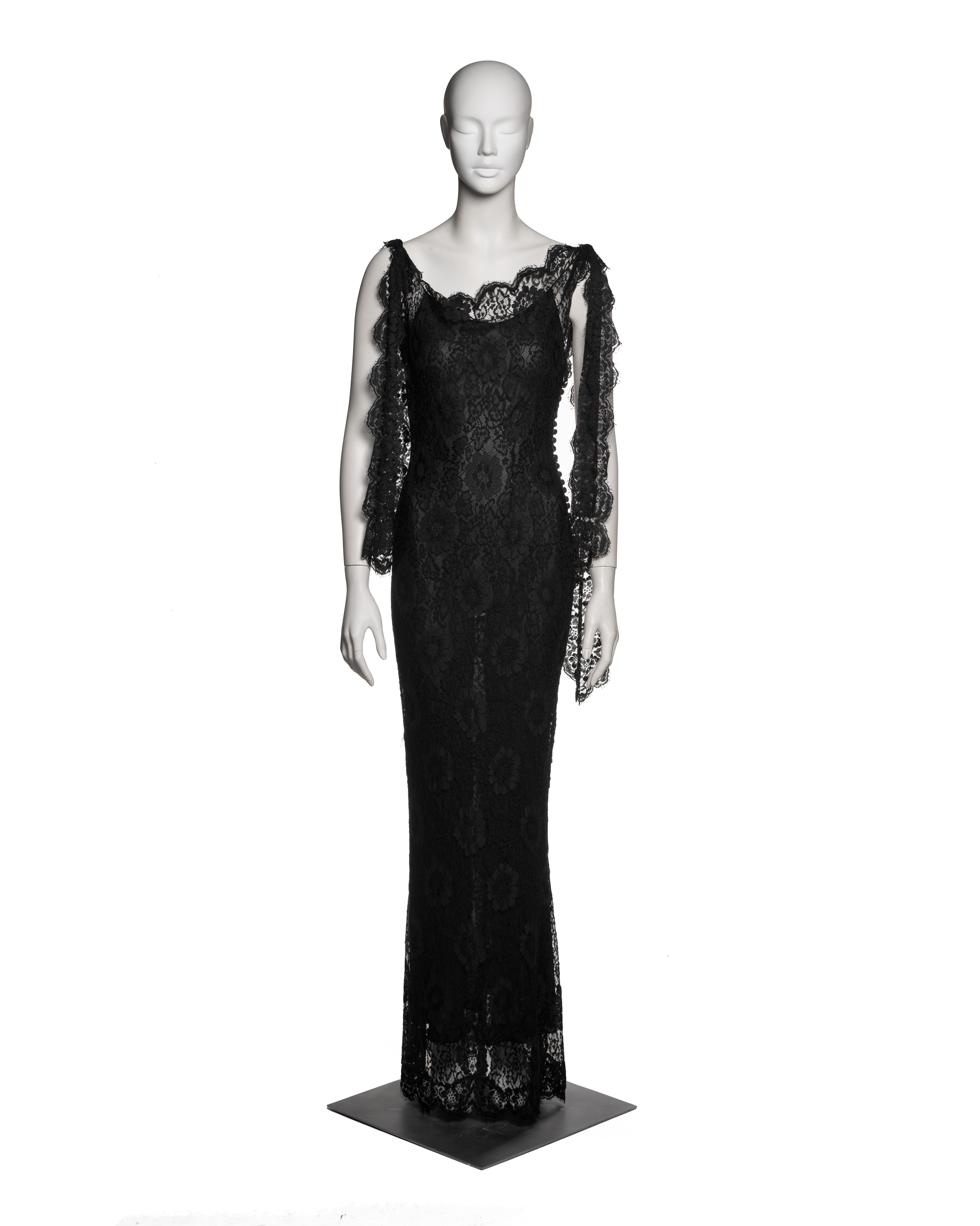 John Galliano Spring-Summer 1998 black lace evening dress, designed as part of an ensemble worn with a coordinating bias-cut silk slip dress. The outer dress is constructed from Chantilly lace with floral motifs, featuring a fitted silhouette, a low