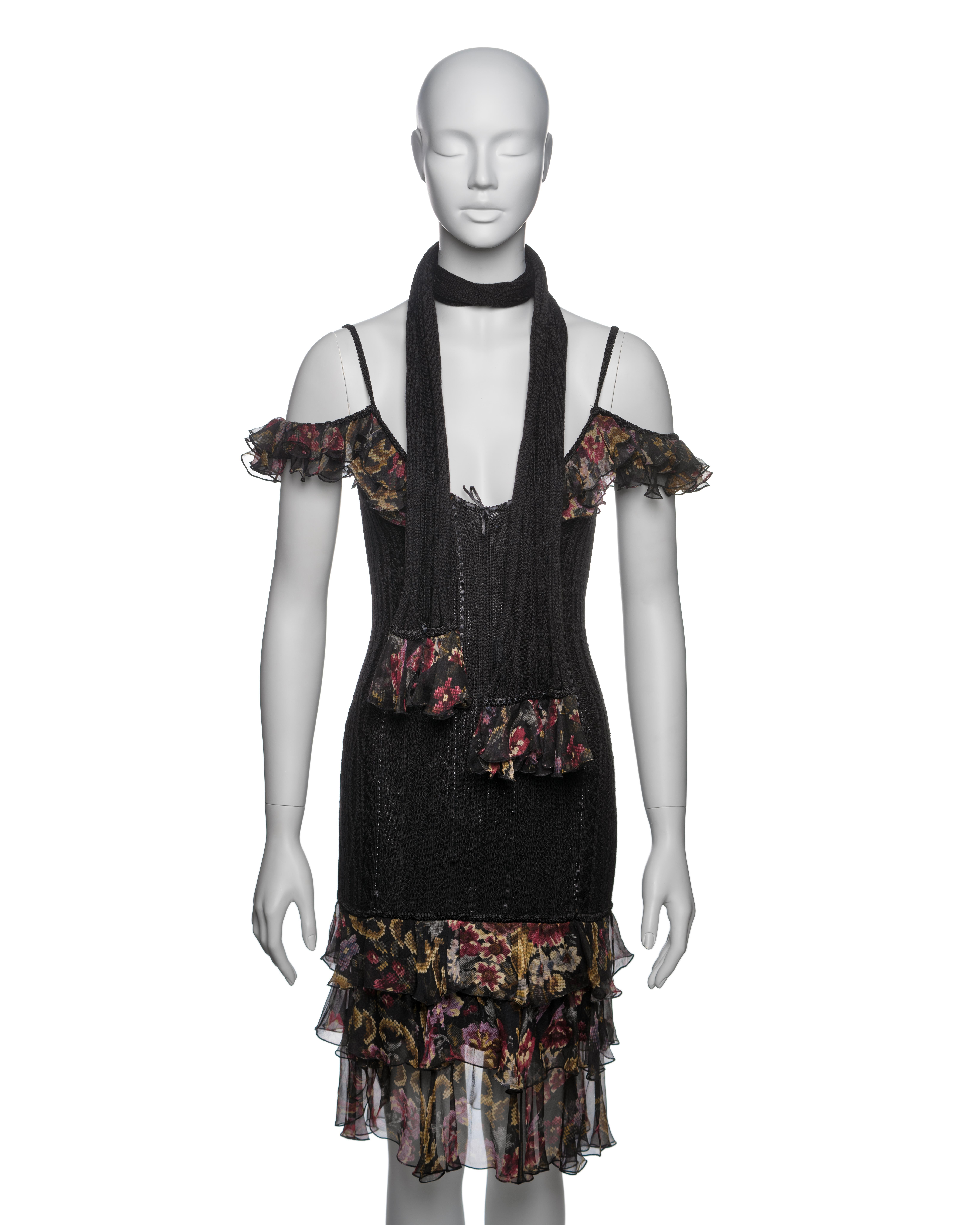 This John Galliano dress and matching scarf from the Fall-Winter 2003 collection are crafted from a black wool/viscose blend with intricate knit patterns, interwoven with tonal black silk ribbons. The dress features floral-printed silk chiffon