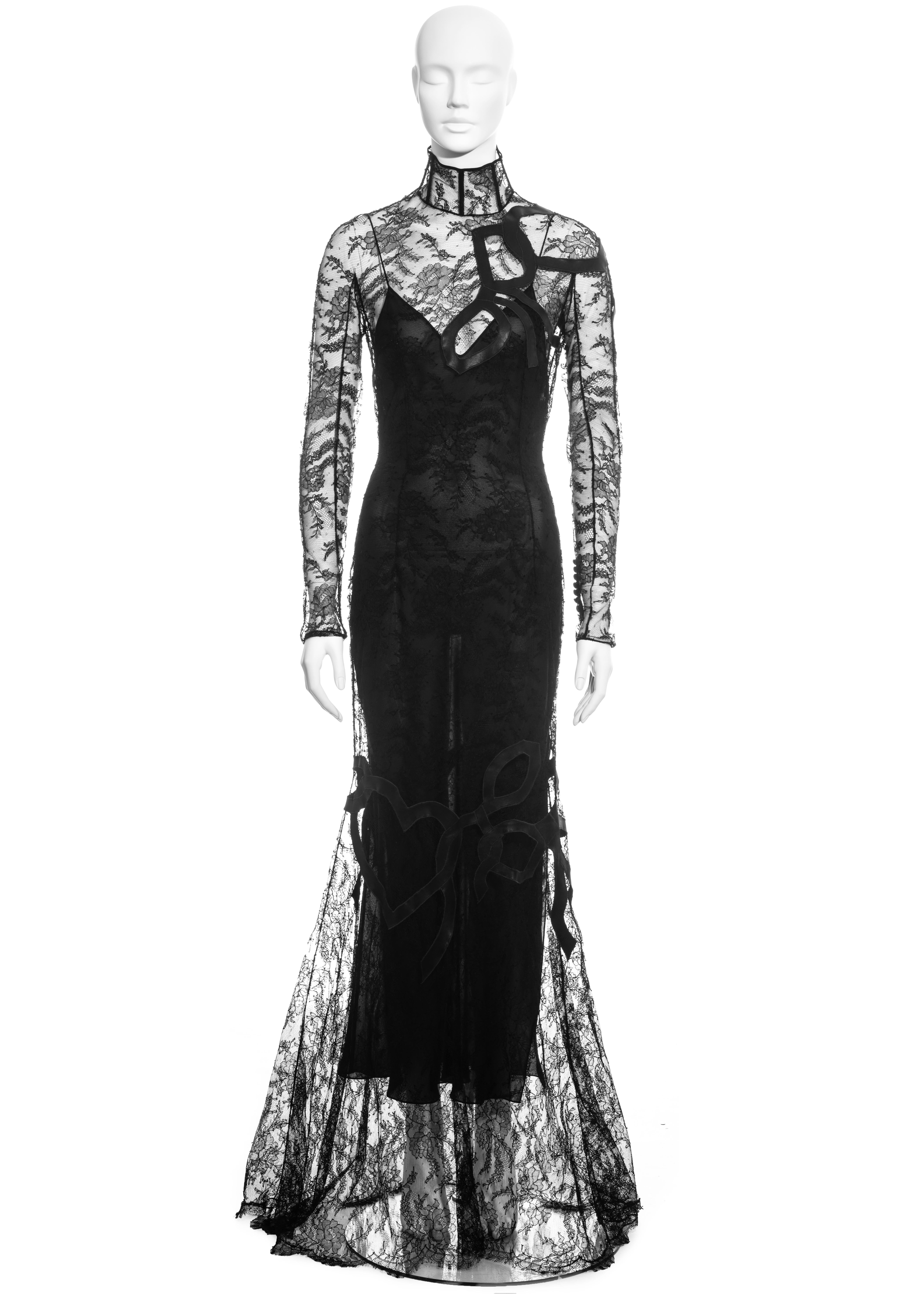 ▪ Black lace trained long-sleeve evening dress
▪ High-neck
▪ Ribbon shaped leather appliqués 
▪ Multiple fabric covered button fastenings 
▪ Detached black silk spaghetti strap slip dress
▪ FR 42 - UK 14 - US 8 
▪ Fall-Winter 2001