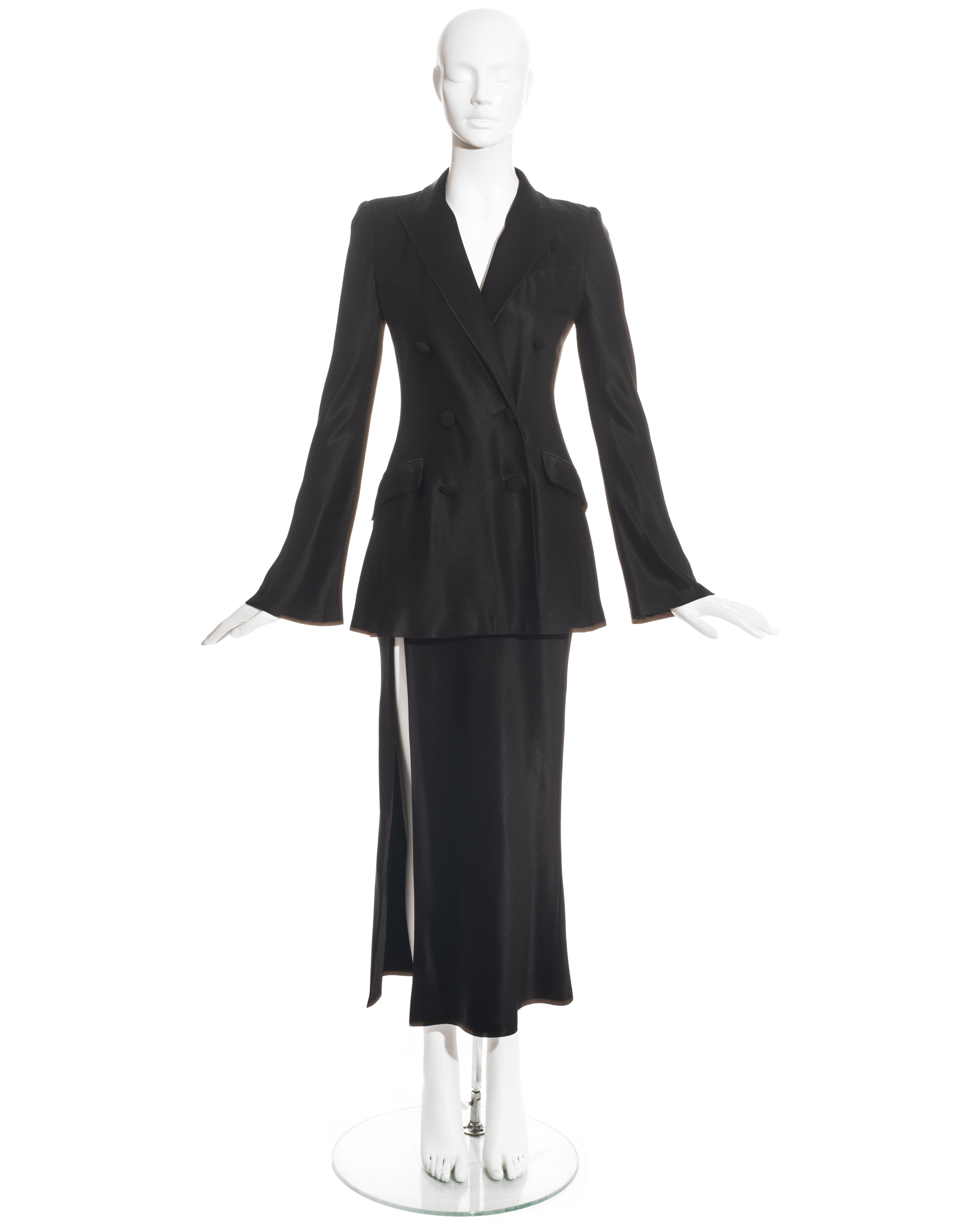 John Galliano black satin skirt suit comprising: double-breasted jacket with cord-wrapped buttons and peak lapel; high waisted ankle-length skirt with high leg slit and cream silk lining. 

Fall-Winter 1994
