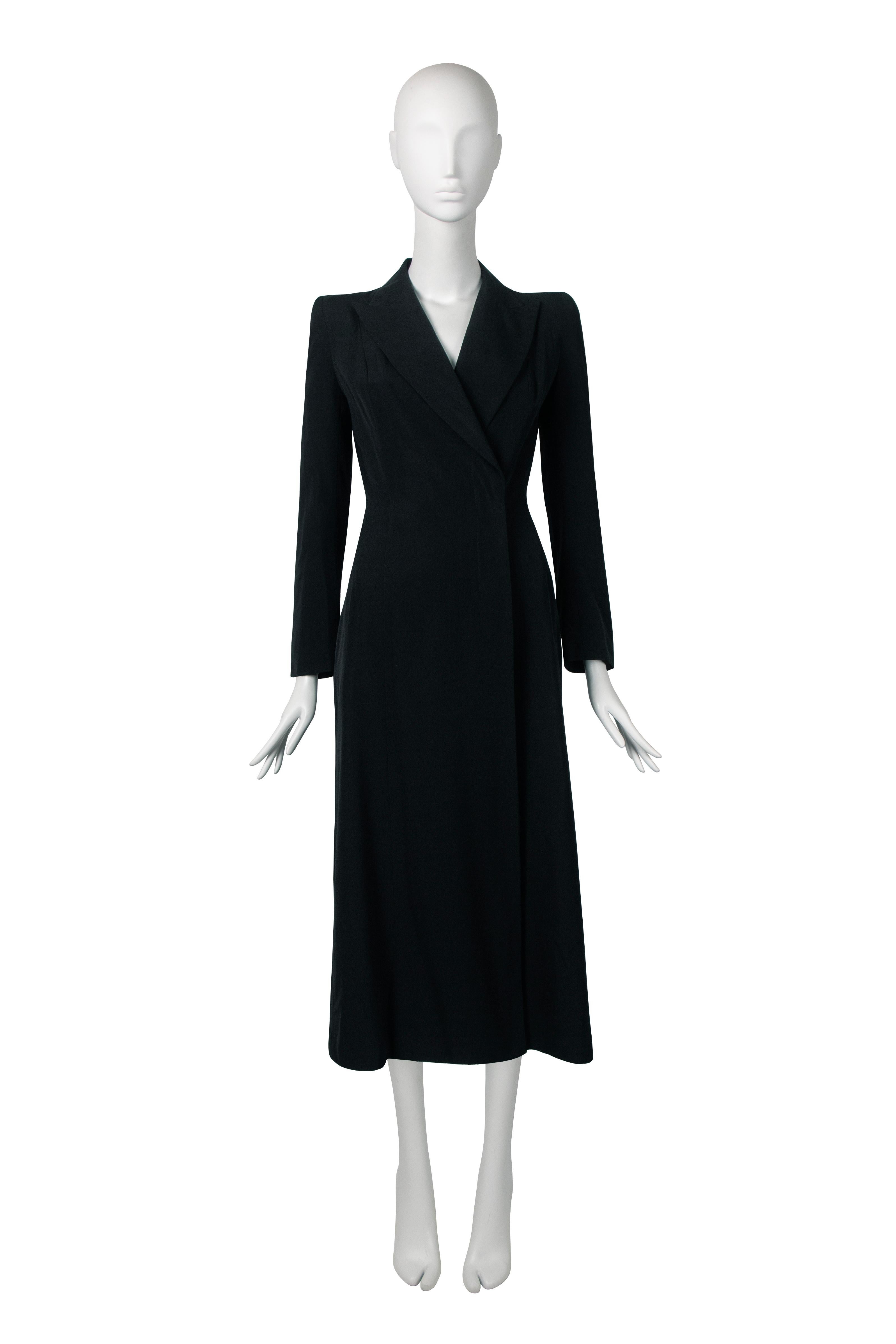A John Galliano wool coat, spring-summer 1996 ‘L’École de Danse’. This sophisticated calf length coat is crafted from black wool gabardine, which gives it a luxurious feel and a sleek look.

The peak lapel and strong shoulders are standout features