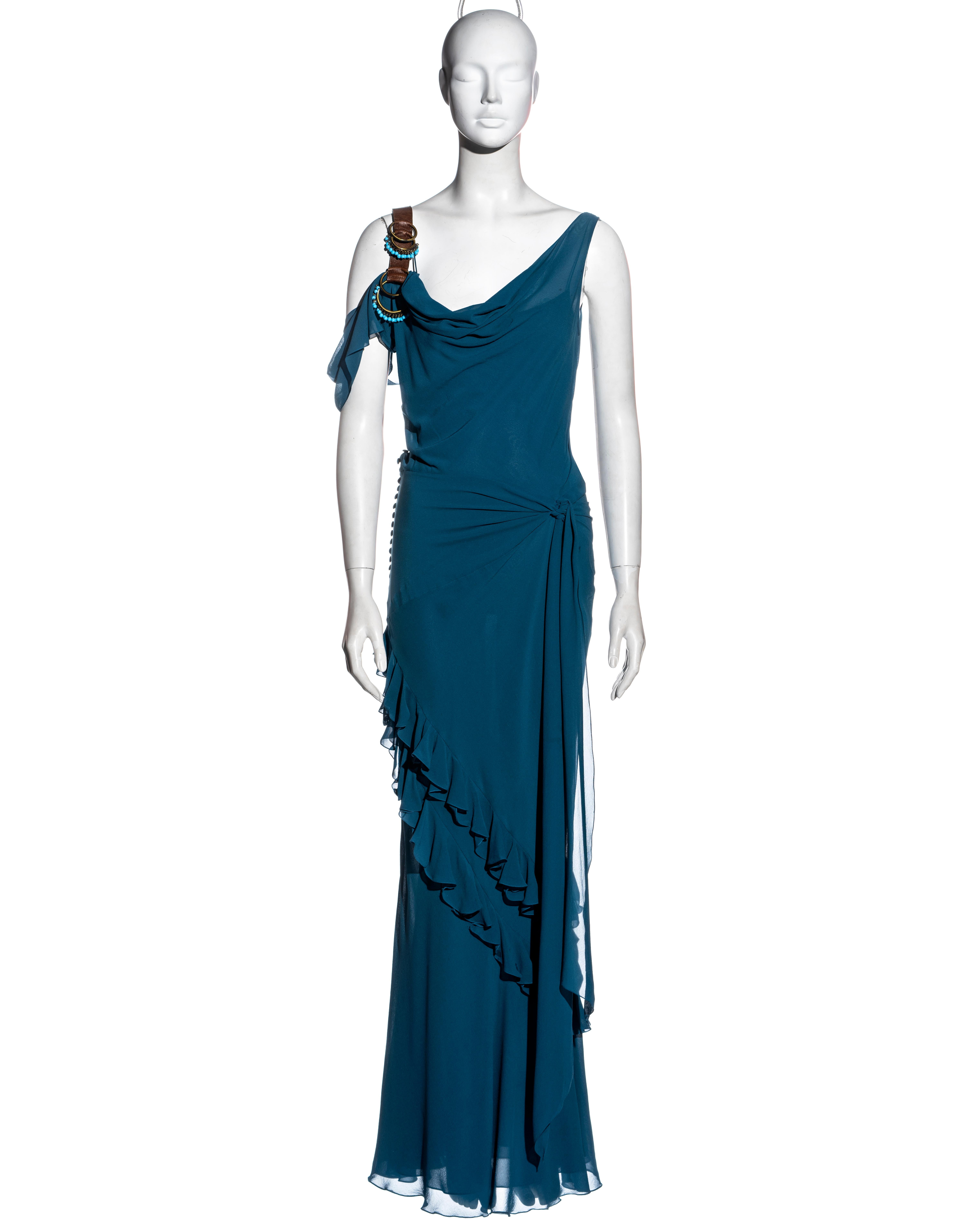 ▪ John Galliano blue silk floor-length evening dress
▪ Cowl neck 
▪ Off-shoulder 
▪ Brass hoops with turquoise beads on the brown leather shoulder strap
▪ Two ties knot at the waist 
▪ Frilled floor-length skirt 
▪ Fabric buttons at the side seam
