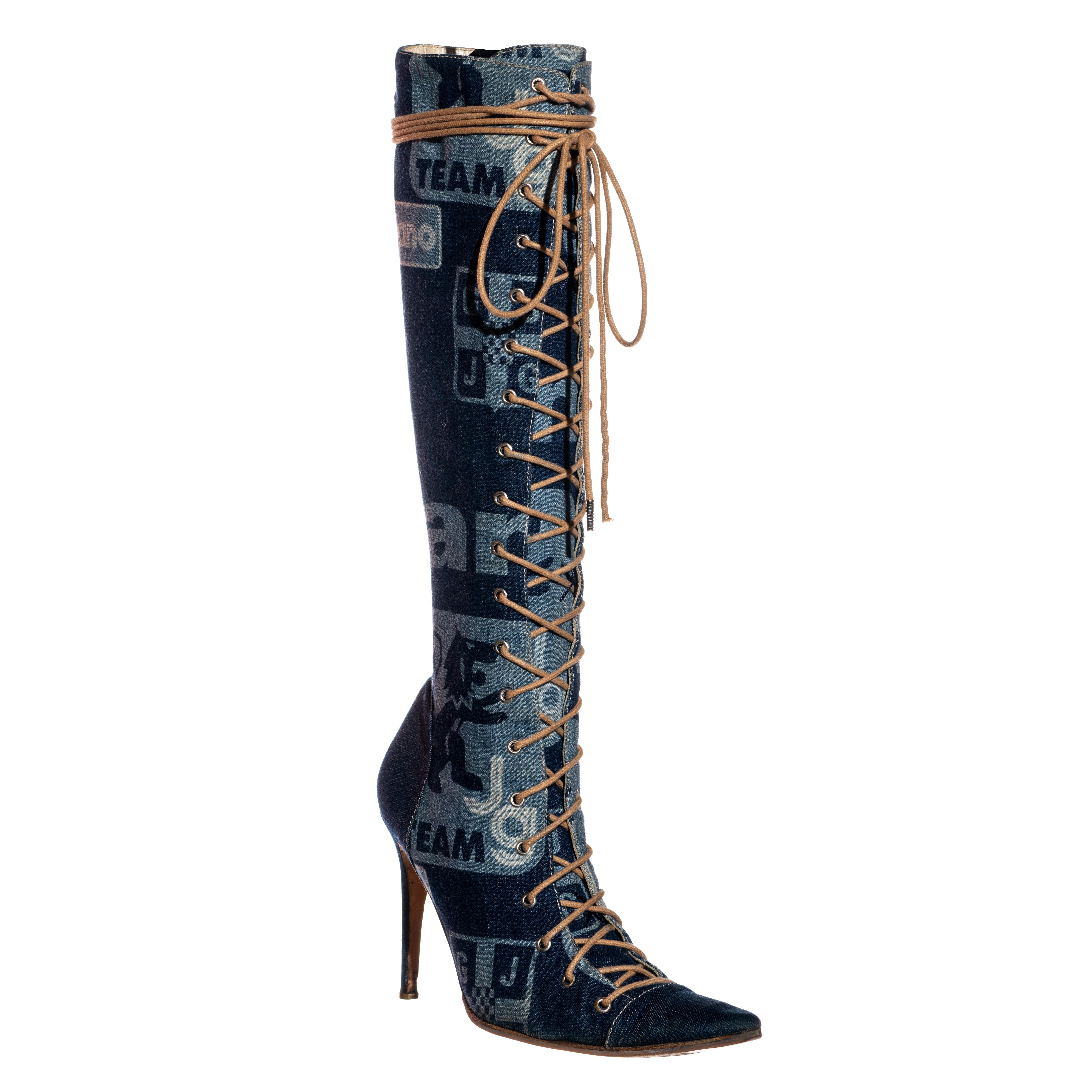 ▪ Kniehohe Stiefel aus blauem Denim von John Galliano 
▪ Druck inspiriert von Fußballabzeichen 
▪ Spitz zulaufende Zehe 
▪ Sohlen aus Leder 
▪ Schnürverschluss 
▪ Reißverschluss an der Innennaht 
▪ Größe: Eur 38
▪ Frühjahr-Sommer 2002